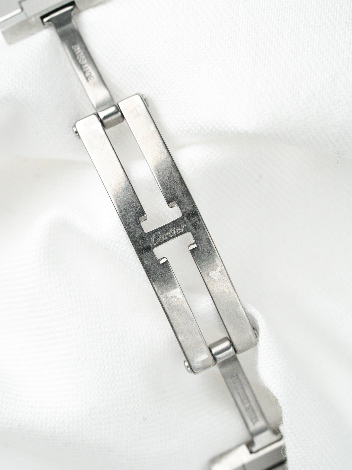 Fermoir de bracelet de montre Cartier en acier inoxydable sur fond blanc