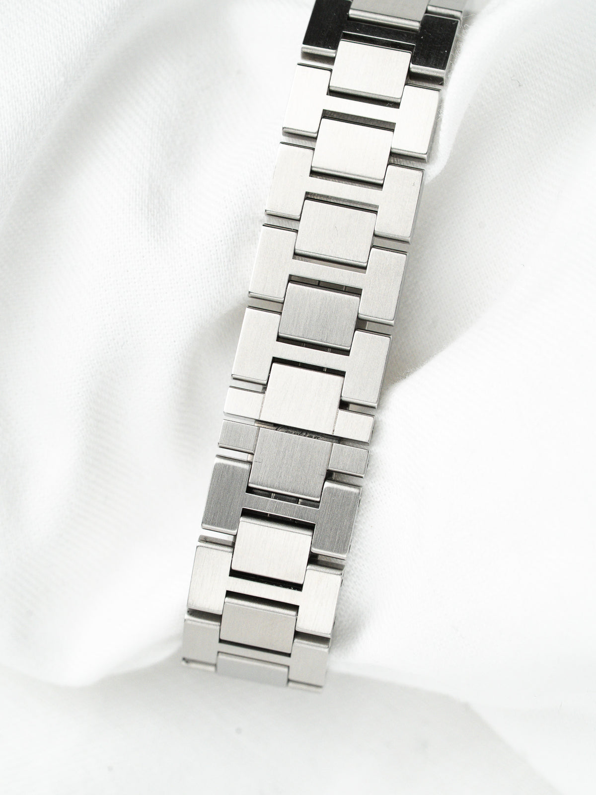 Bracelet de montre en acier inoxydable argenté posé sur un tissu blanc