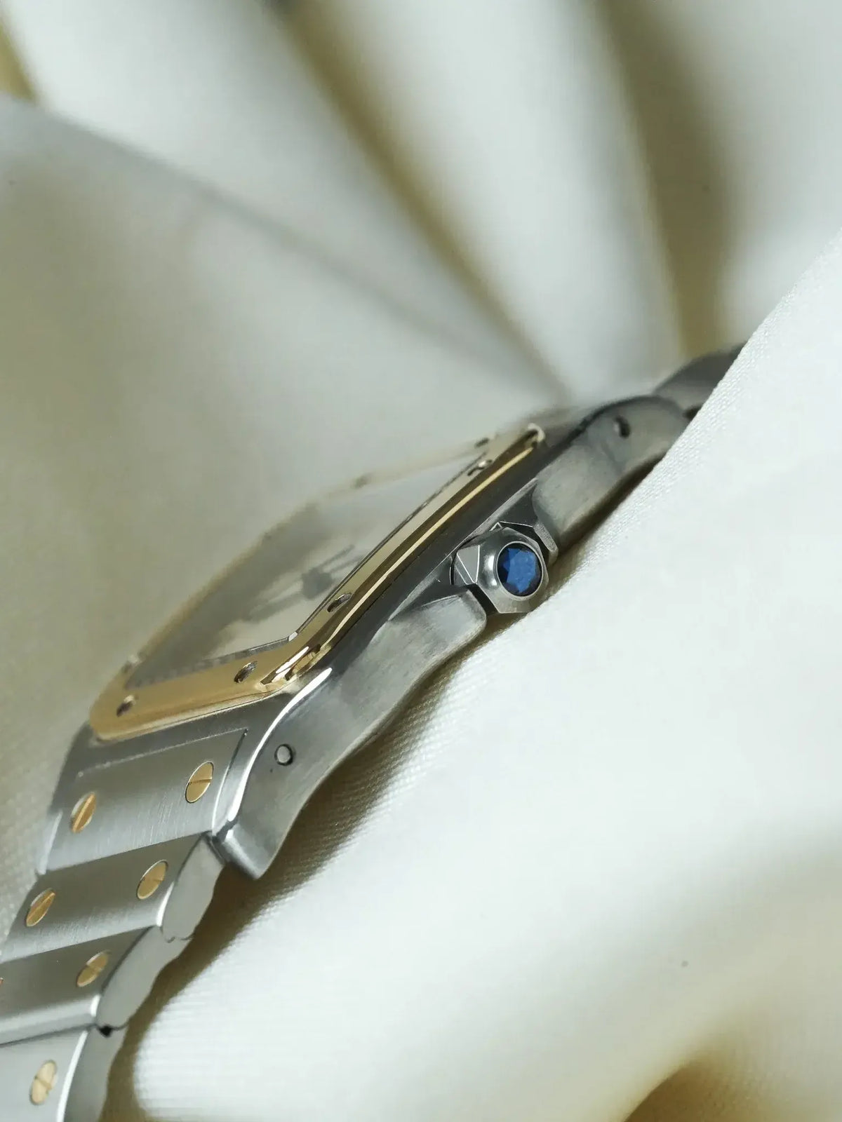 Cartier Santos watch with steel and gold case, blue sapphire crown, on white fabric