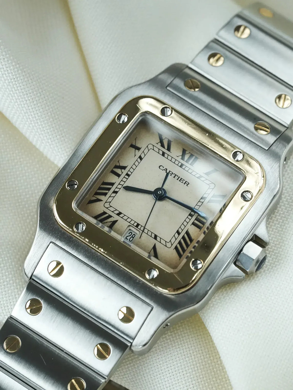 Cartier Santos vintage watch with silver case, cream dial, Roman numerals, and gold screws