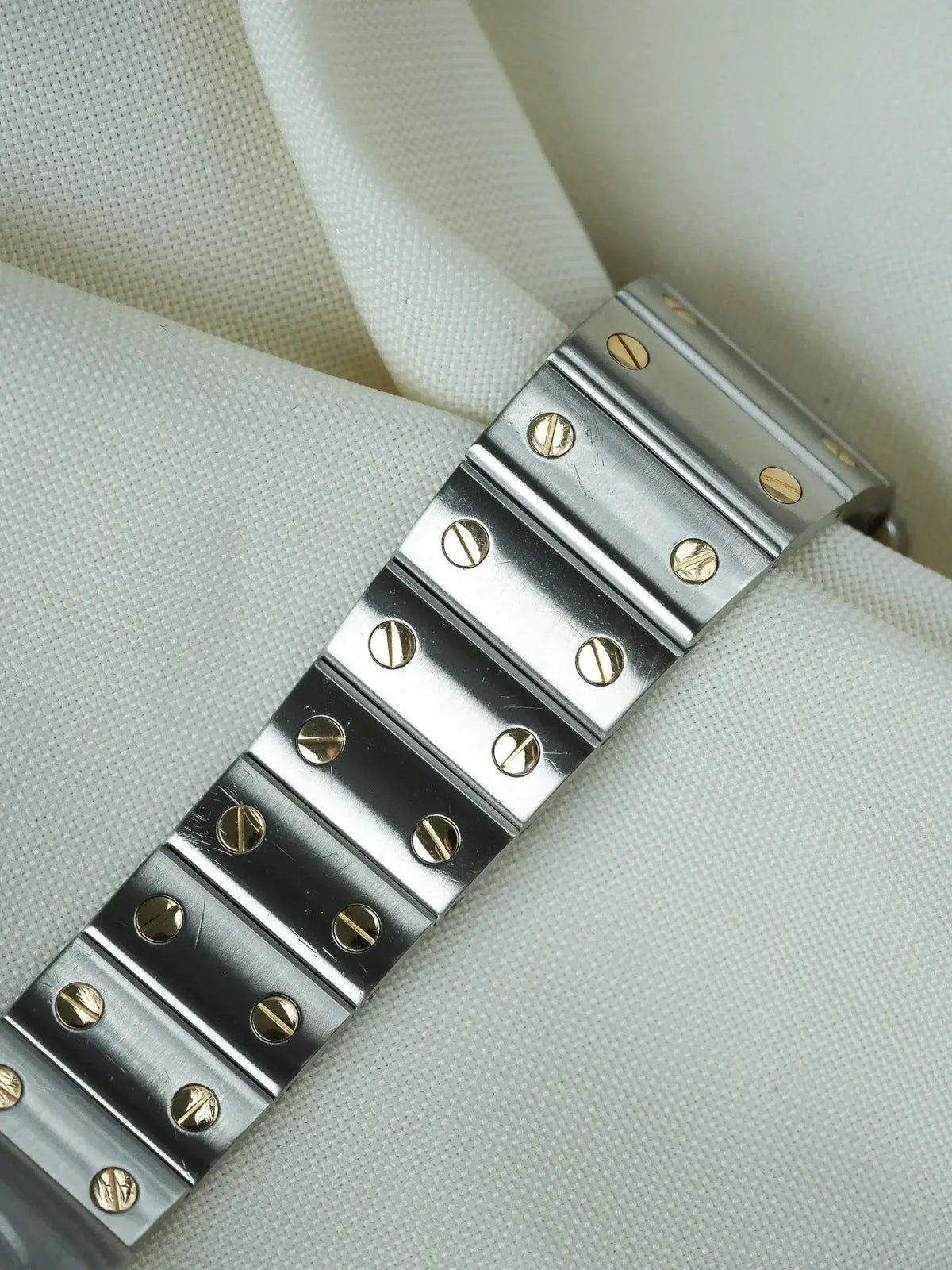 Vintage Rolex Oyster bracelet in stainless steel with gold screws, displayed on fabric