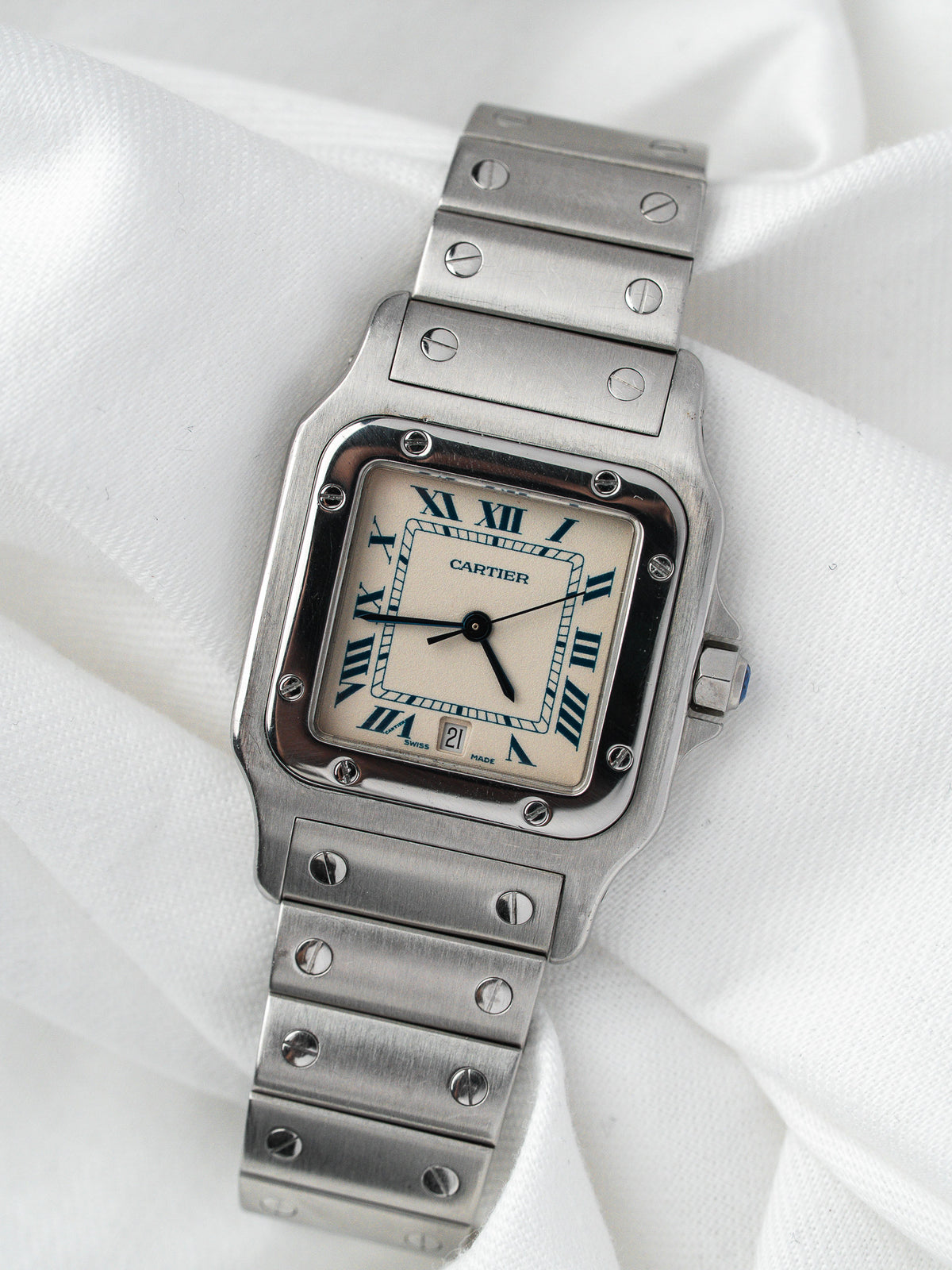 Montre Cartier vintage en acier, boîtier rectangulaire et cadran blanc, sur fond blanc