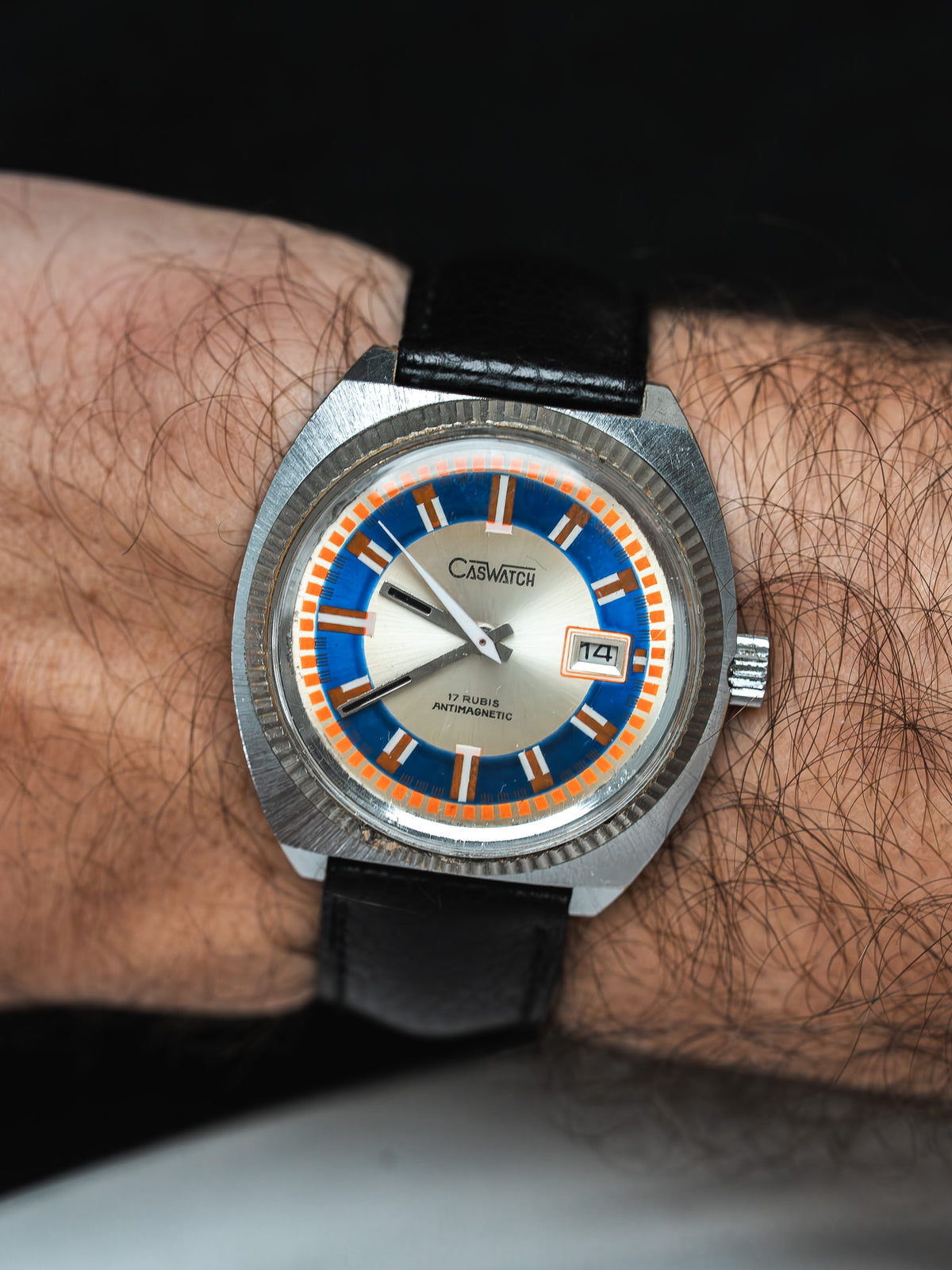 Caswatch vintage watch with blue and orange dial, black leather strap, worn on wrist