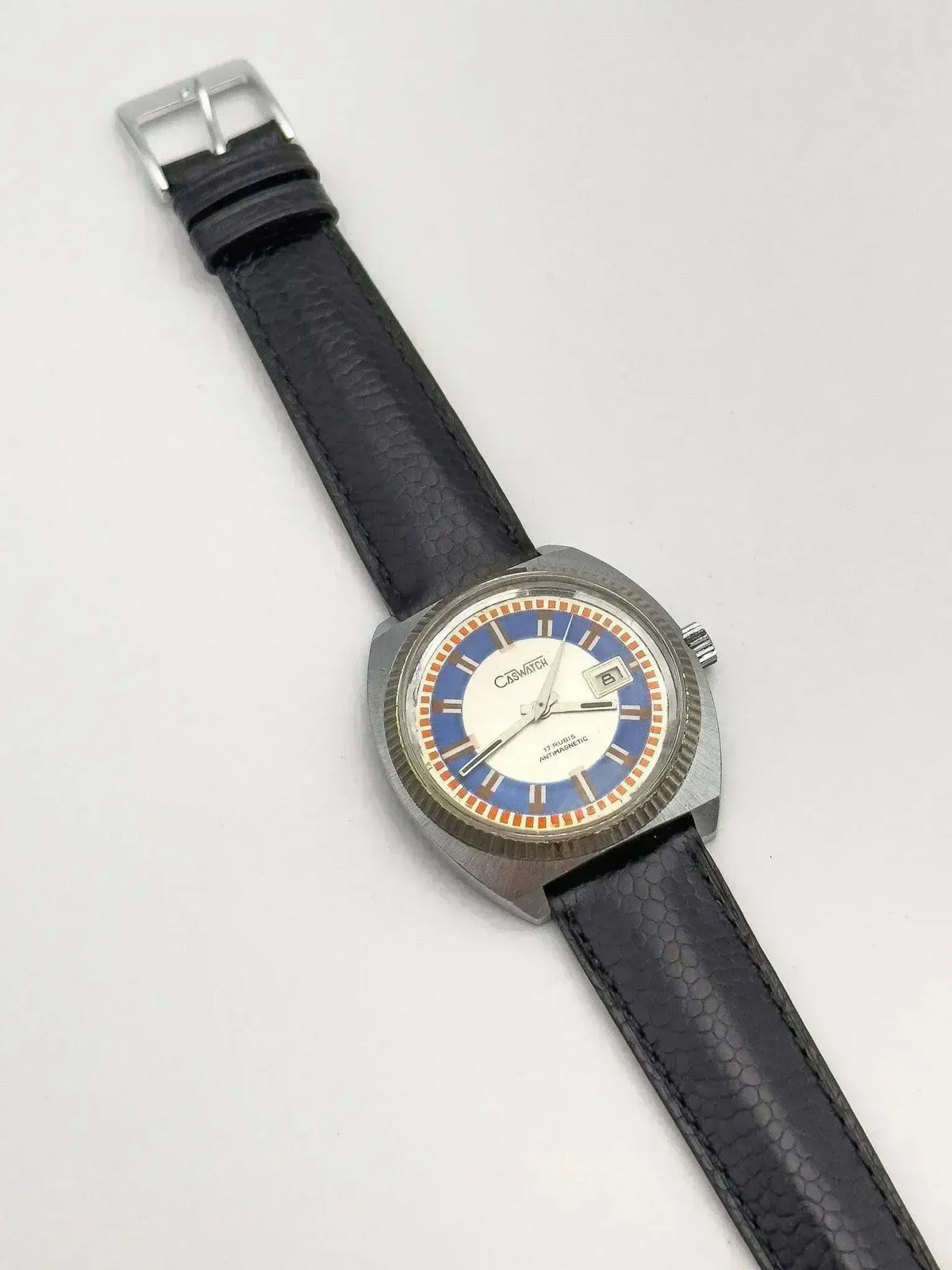 Vintage Casio watch with blue and white dial, black textured strap, silver case on white background