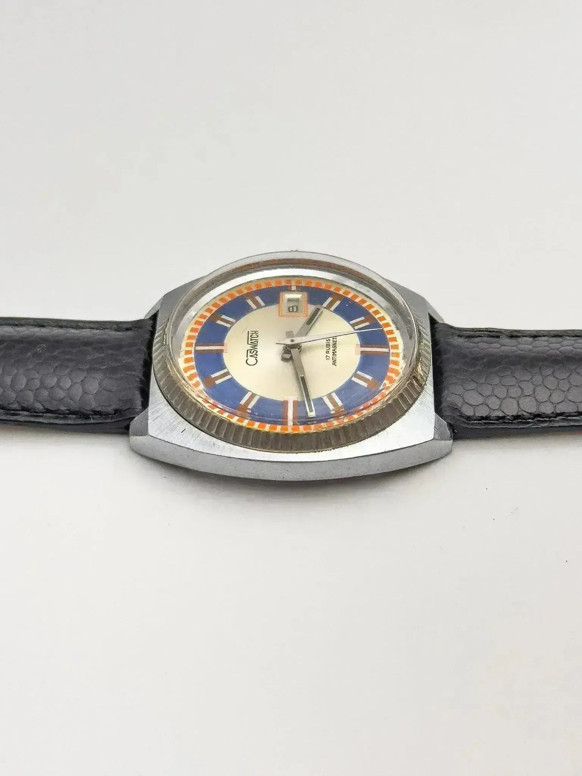 Vintage Casio watch with blue and orange dial, black textured strap, silver case