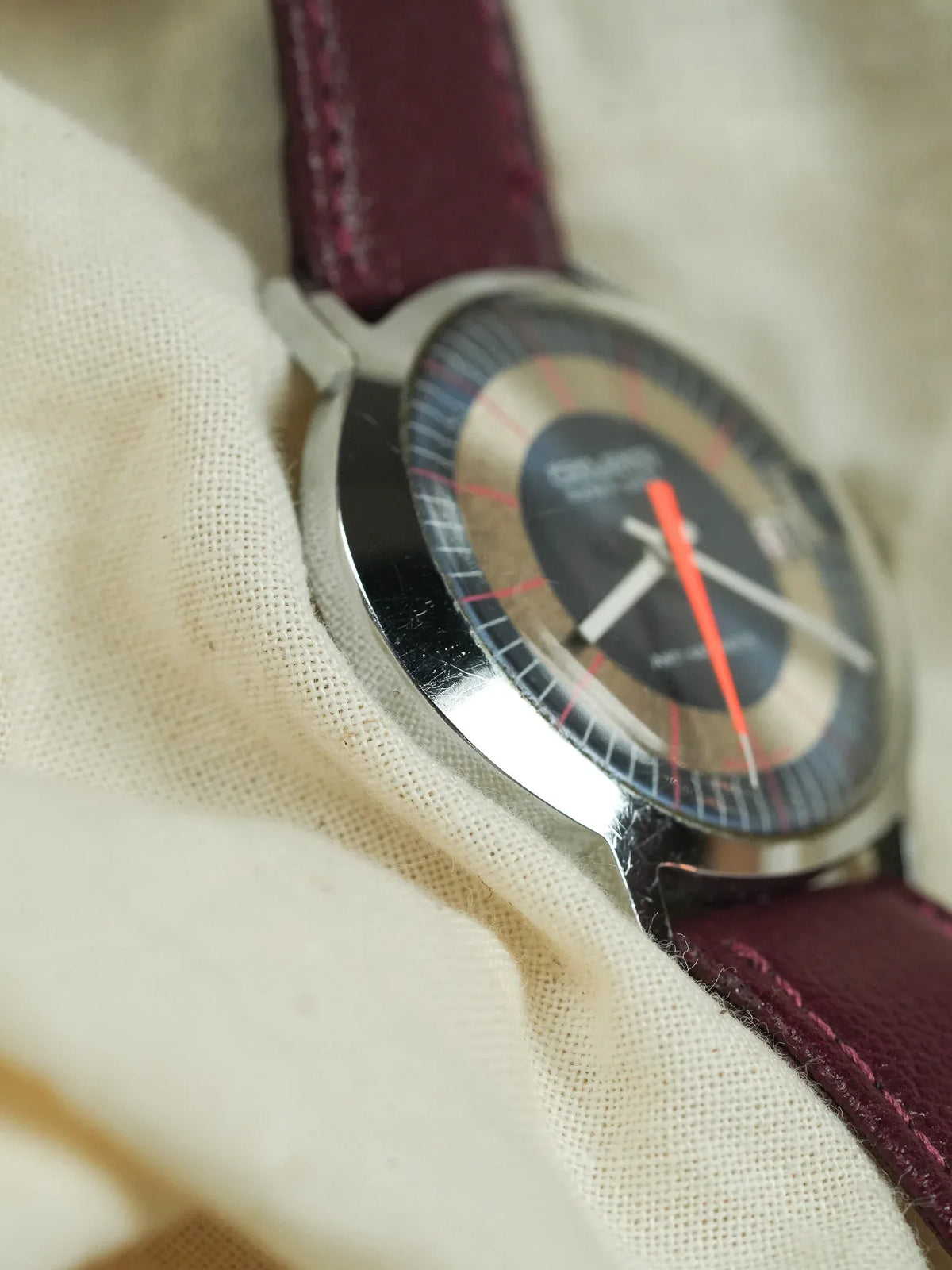 Omega vintage watch with silver case, black dial, red second hand, burgundy leather strap