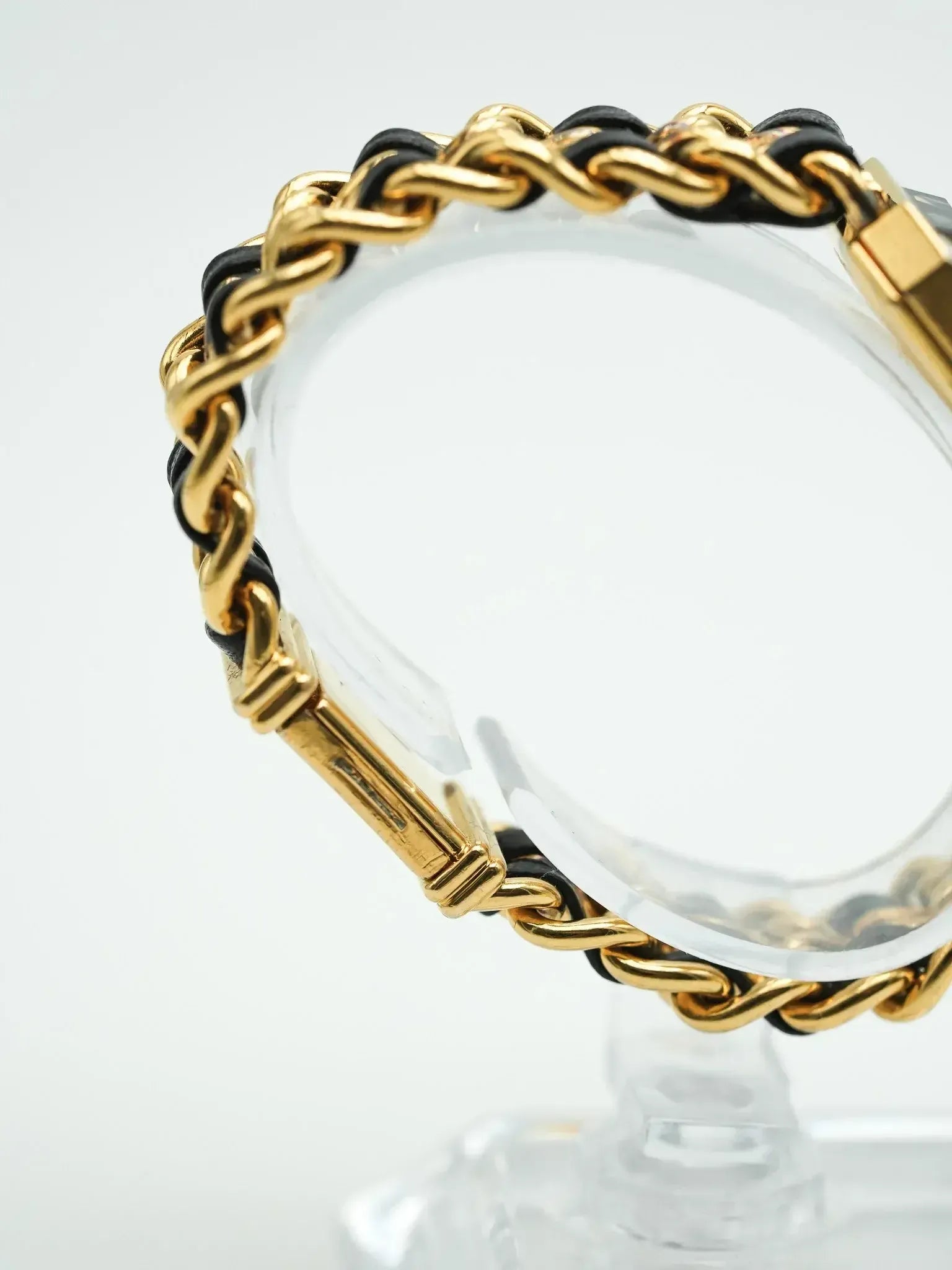 Vintage Cartier bracelet with gold chain and black leather, displayed on stand