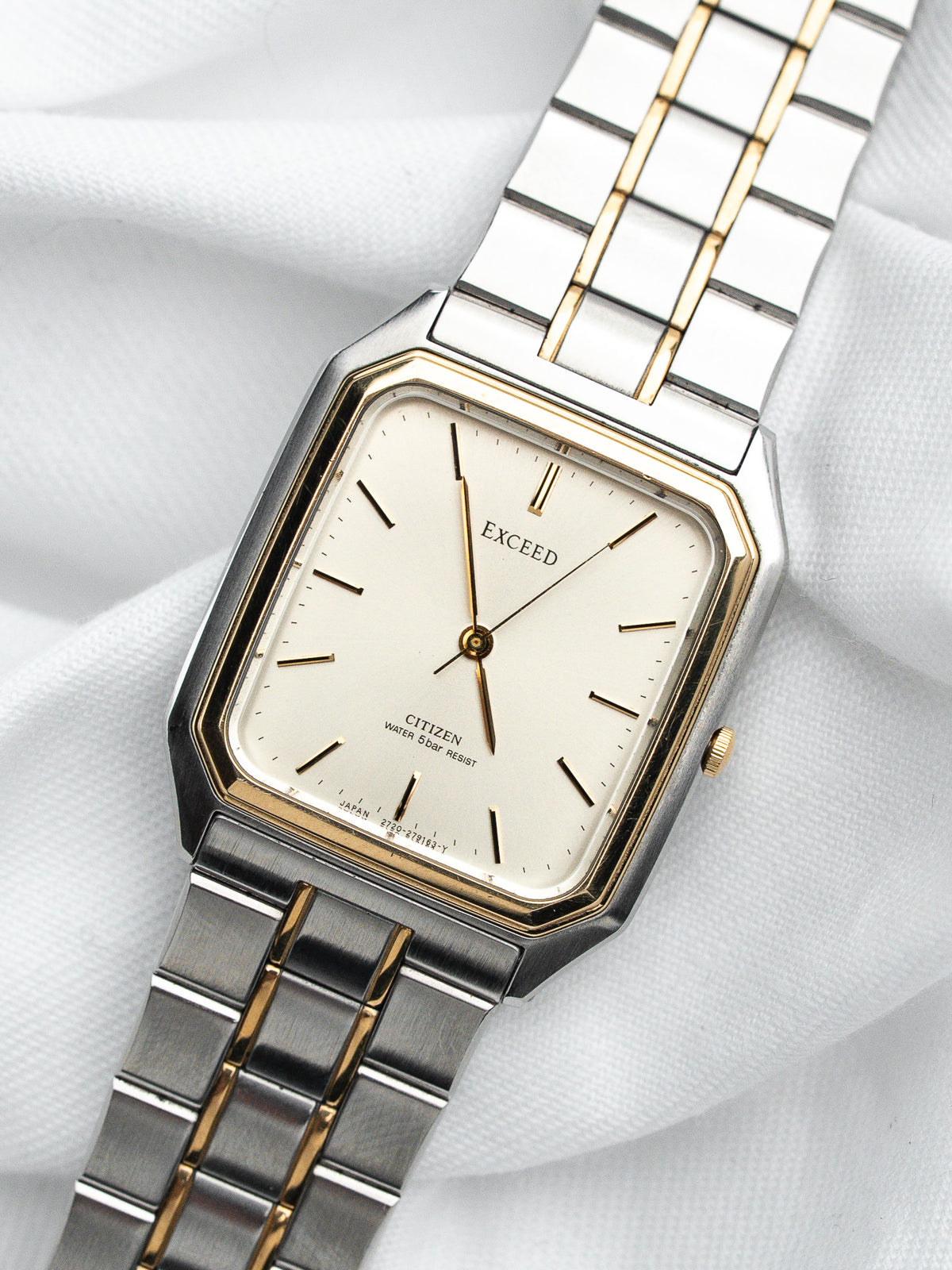 Montre vintage Citizen Exceed rectangulaire avec cadran blanc et bracelet en acier bicolore.