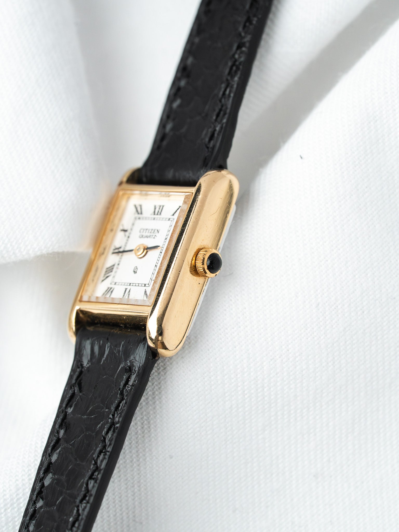 Citizen quartz watch with gold case, white dial, Roman numerals, black leather strap