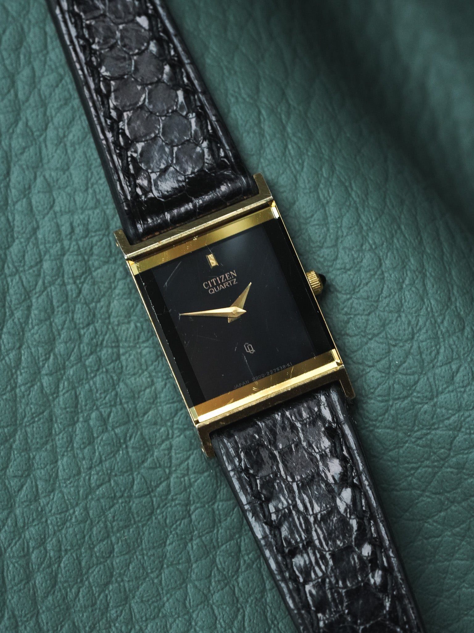 Citizen Quartz vintage watch with gold case, black dial, and textured strap on green leather