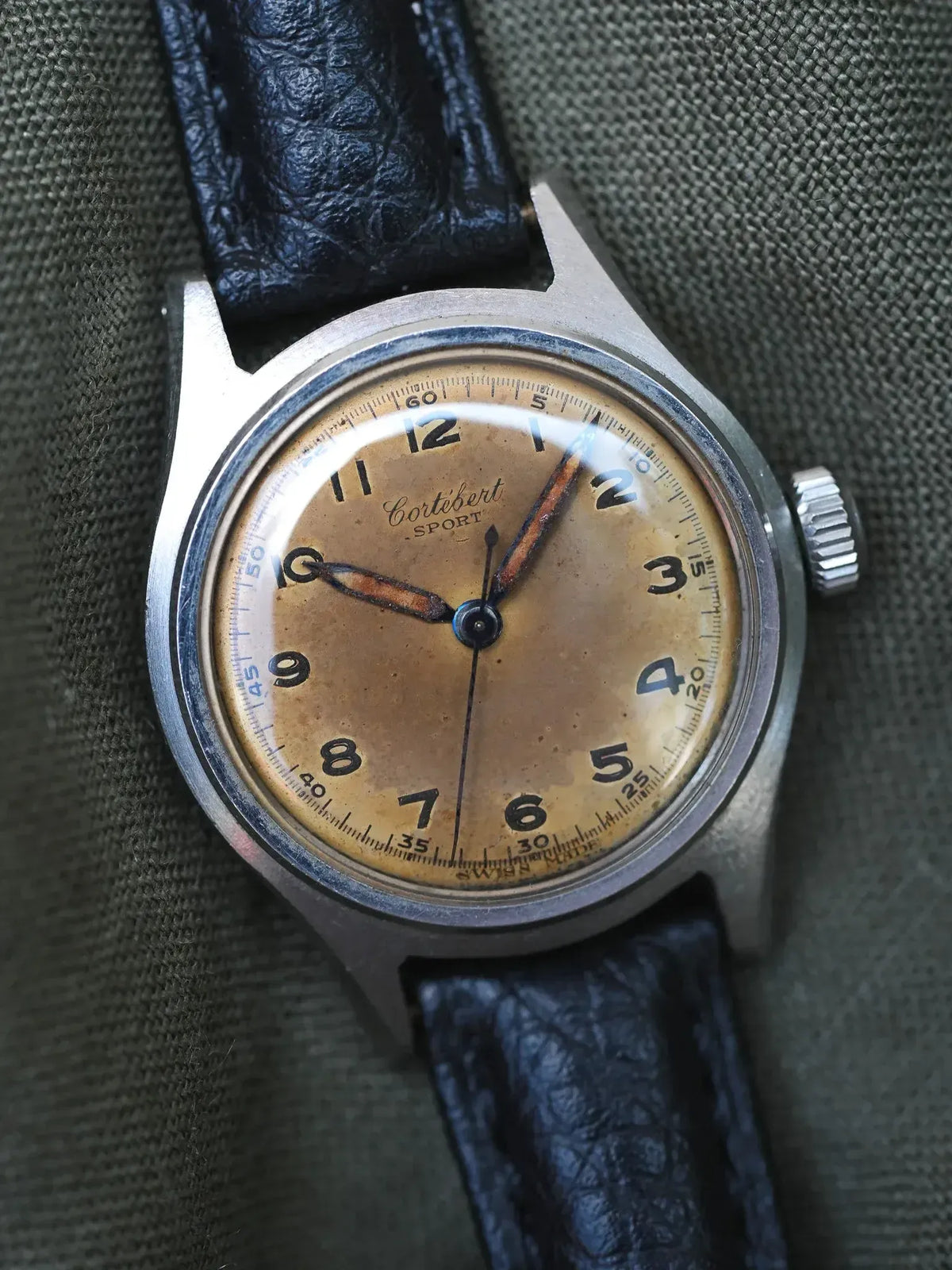 Vintage Cortébert Sport watch with aged dial, steel case, and black leather strap
