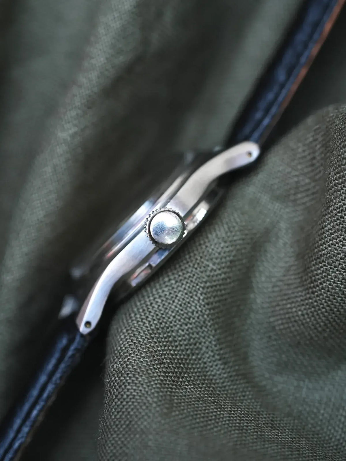 Vintage Cartier watch with blue leather strap, silver case, crown detail on fabric