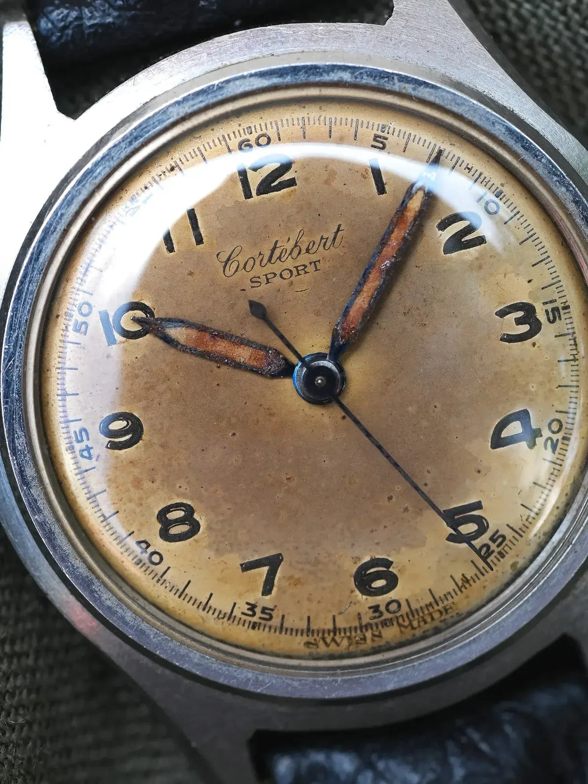Vintage Cortébert Sport watch with aged cream dial, black numerals, and steel case