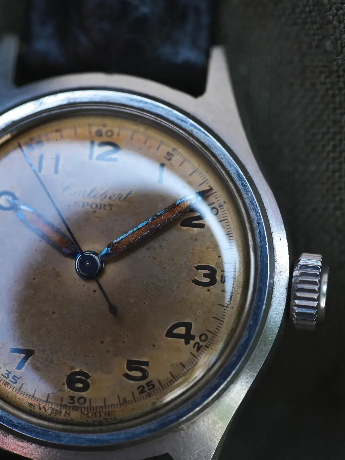 Vintage Eterna Sport watch with aged cream dial, steel case, and black leather strap