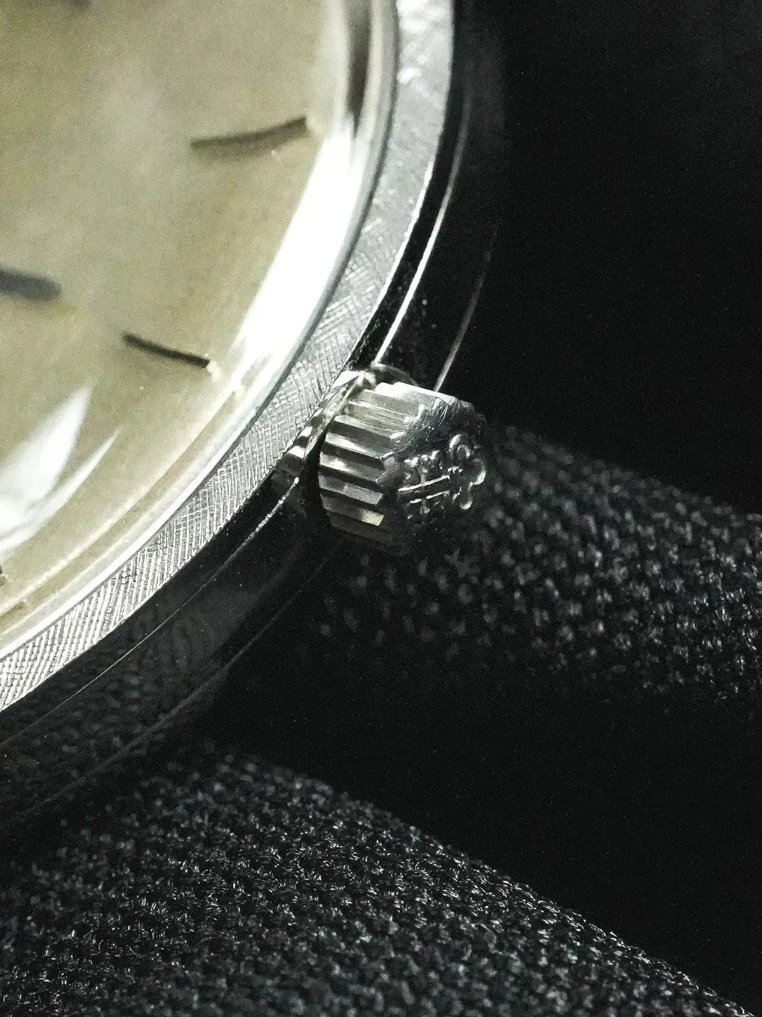 Vintage Rolex watch with fluted bezel and silver dial on dark fabric