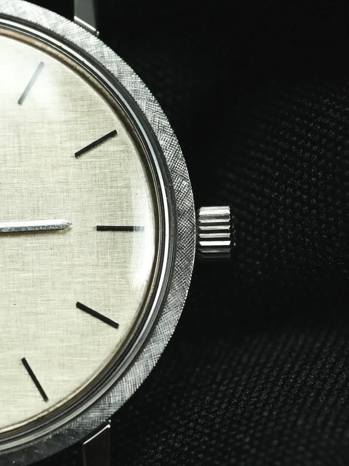 Vintage Omega watch with silver dial, textured bezel, and black marker indices
