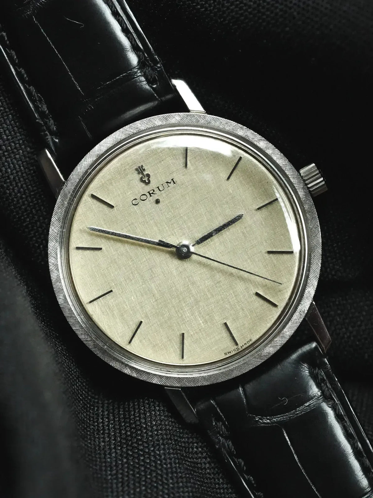 Vintage Corum watch with silvered dial, textured bezel, and black leather strap
