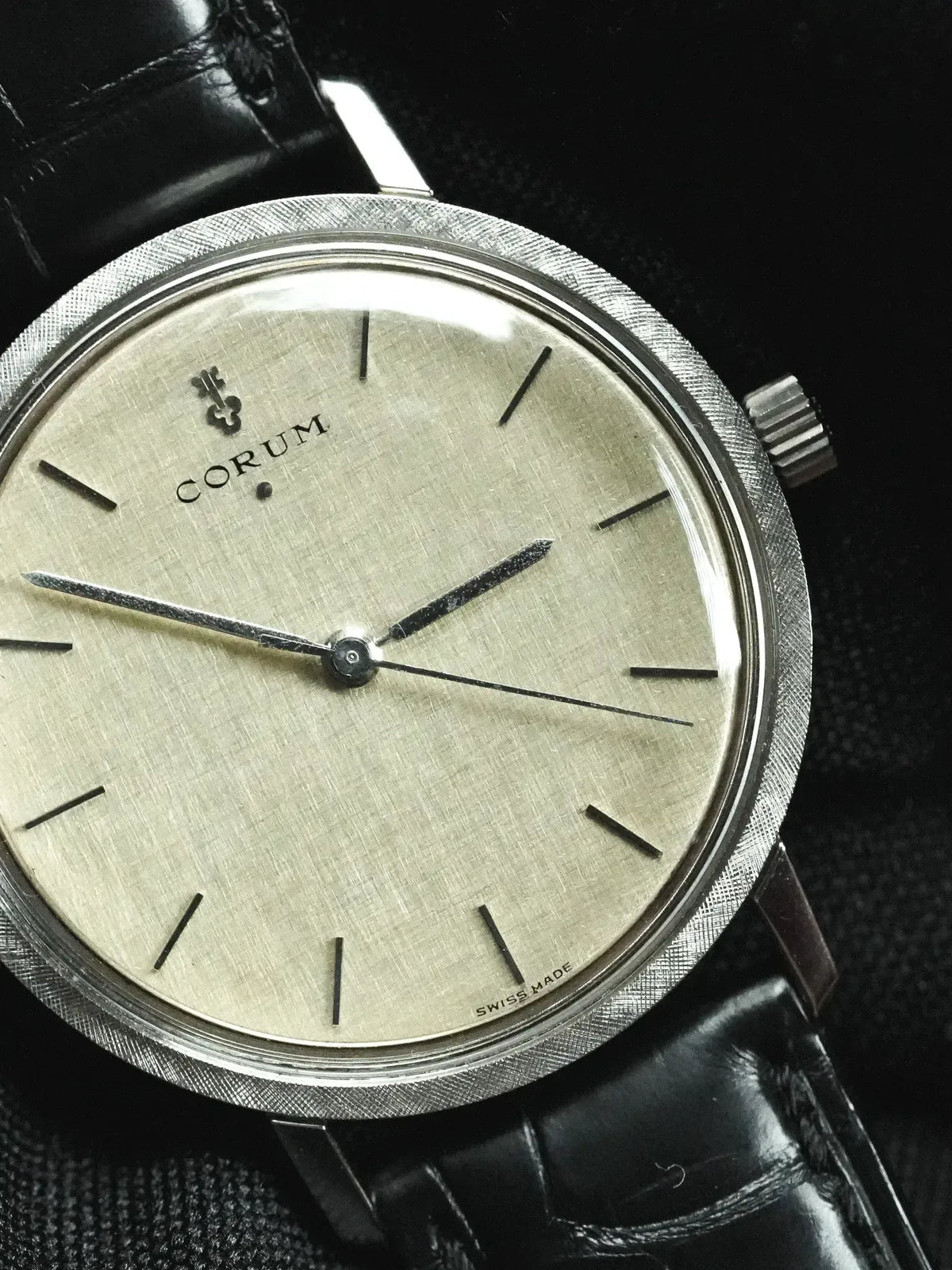 Corum vintage watch with silvered dial, textured bezel, and black leather strap