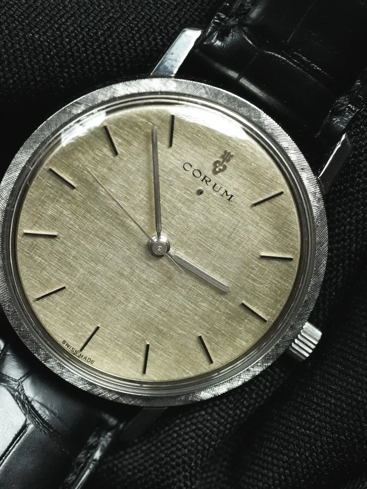 Vintage Corum watch with textured gold dial, steel case, black leather strap