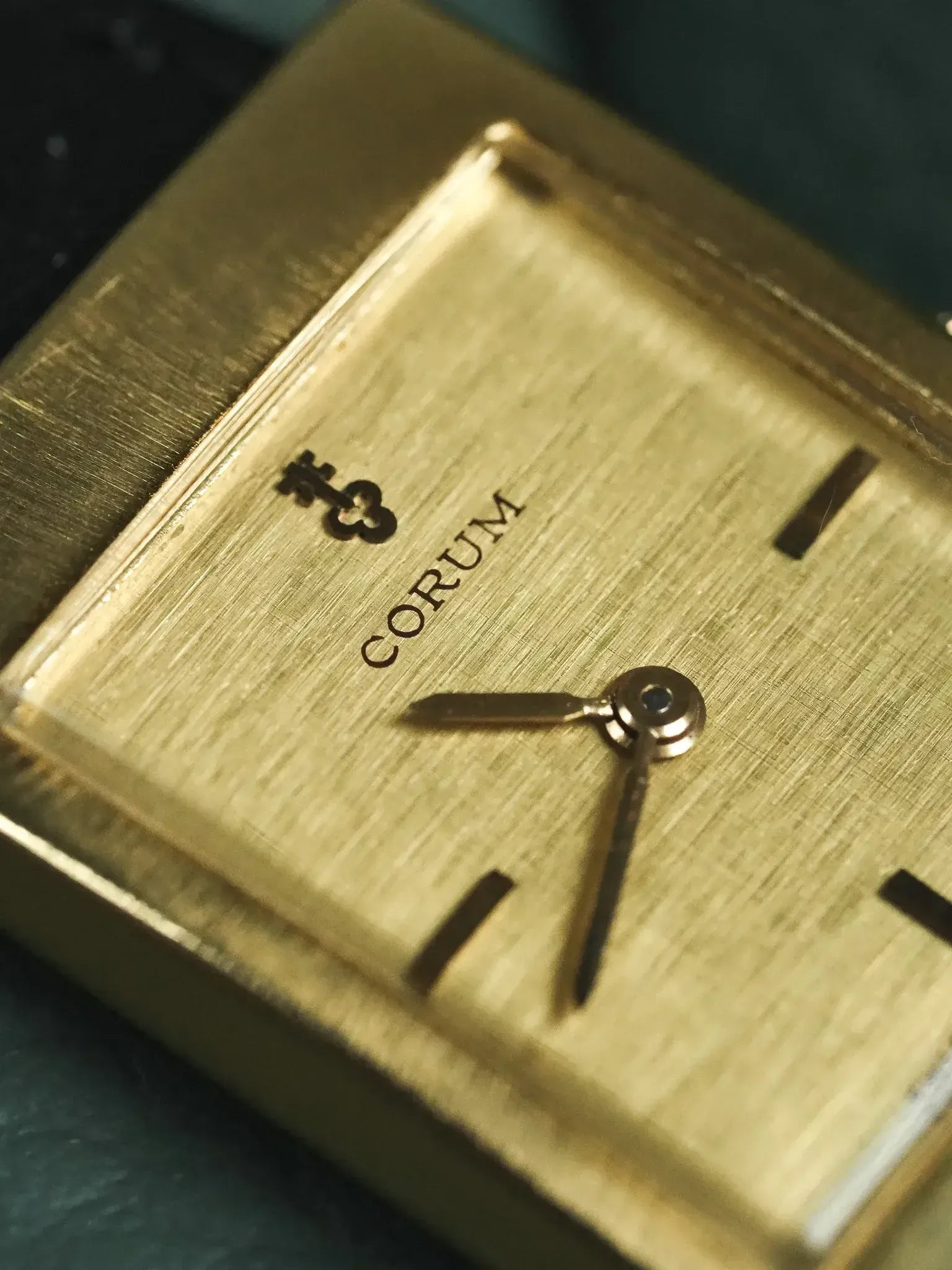 Corum vintage watch with gold textured dial, rectangular case, and baton markers
