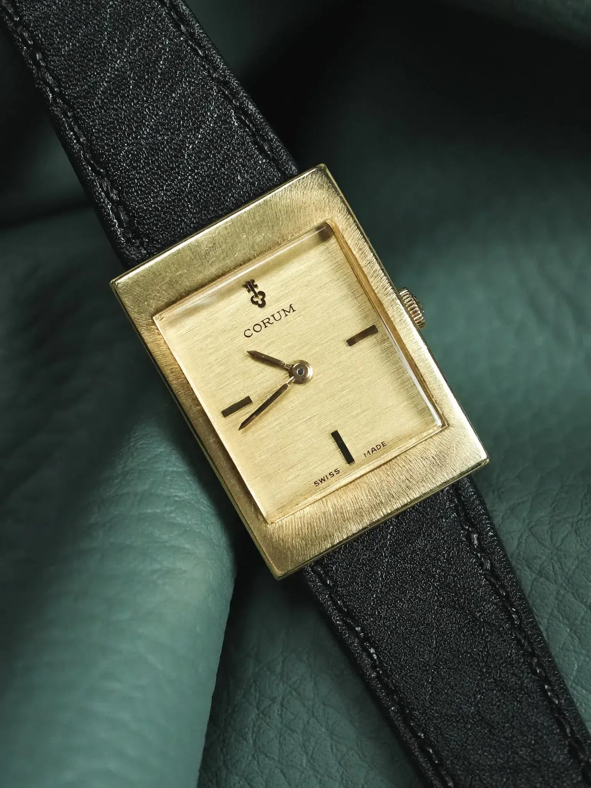 Corum vintage watch with gold square case, black leather strap, and minimalist dial