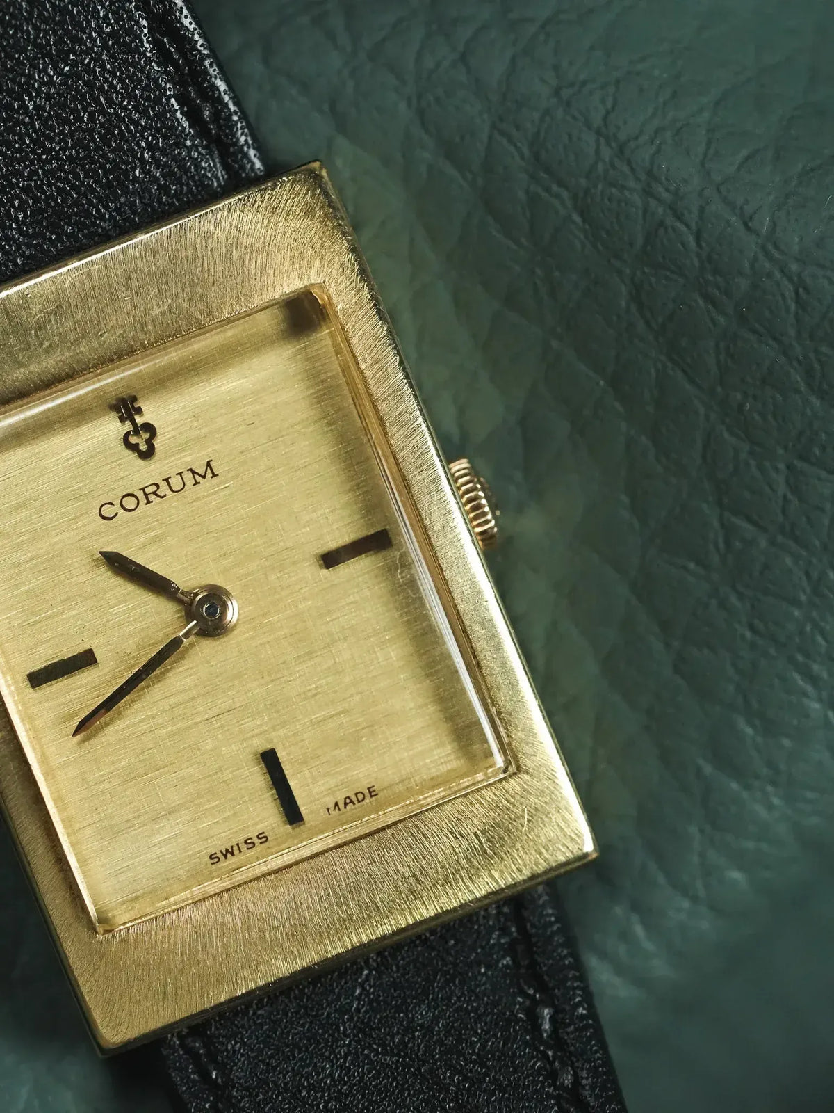 Corum vintage watch with gold square case, brushed dial, black leather strap