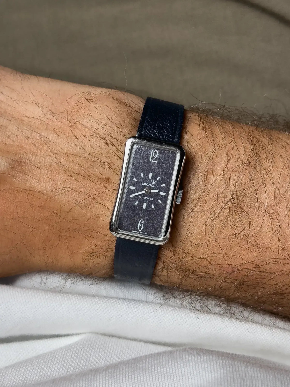 Cronel vintage watch with rectangular case, dark dial, and blue leather strap on wrist