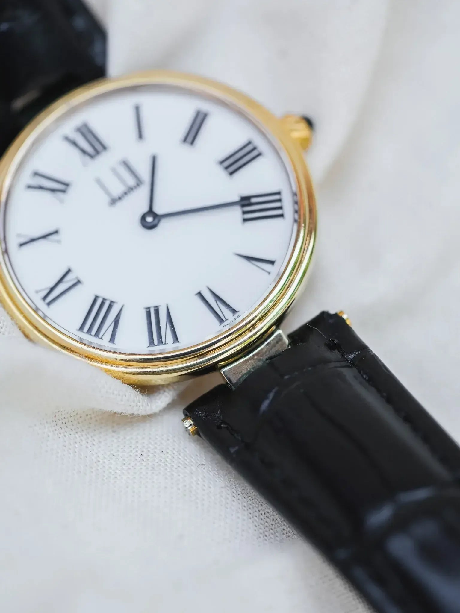 Vintage Cartier watch with gold case, white dial, Roman numerals, black leather strap