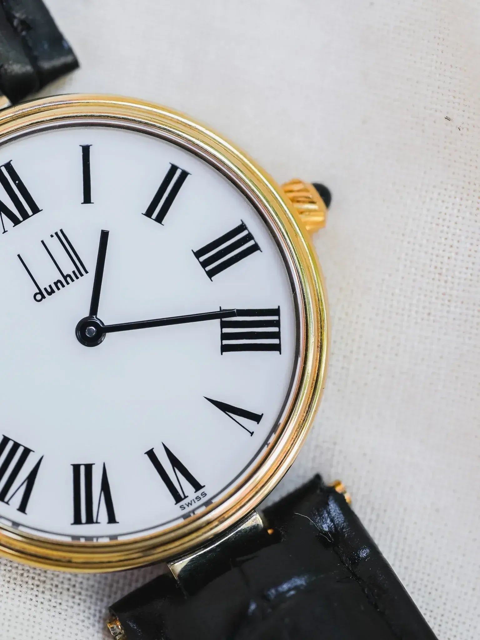 Dunhill vintage watch with gold case, white dial, black Roman numerals, and black leather strap