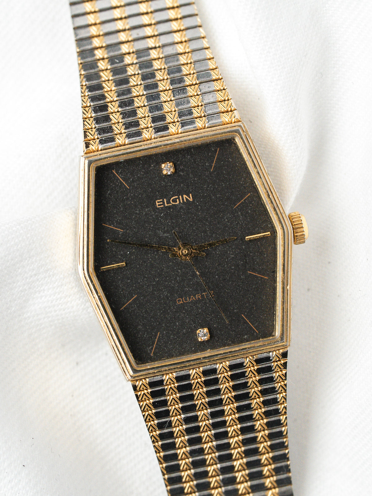 Elgin vintage quartz watch with black dial, gold accents, and patterned bracelet