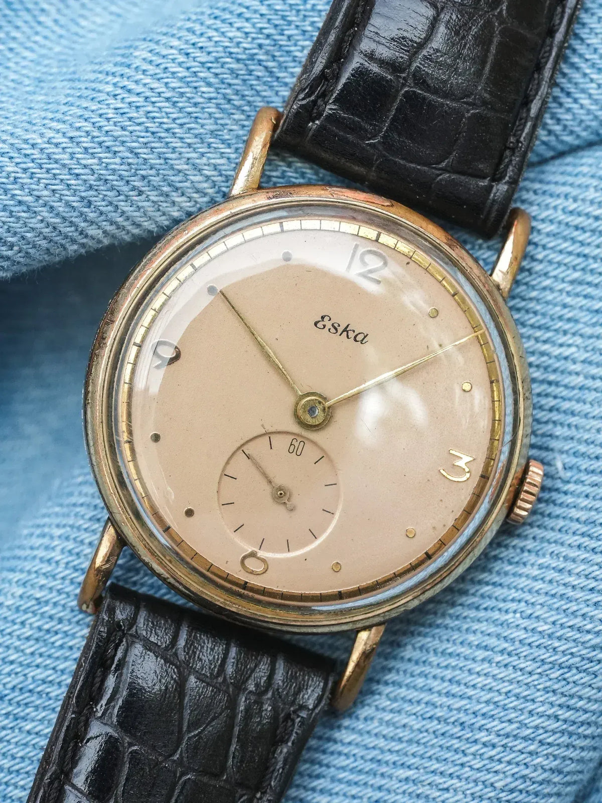 Vintage Eska watch with cream dial, gold hands, black alligator strap on denim