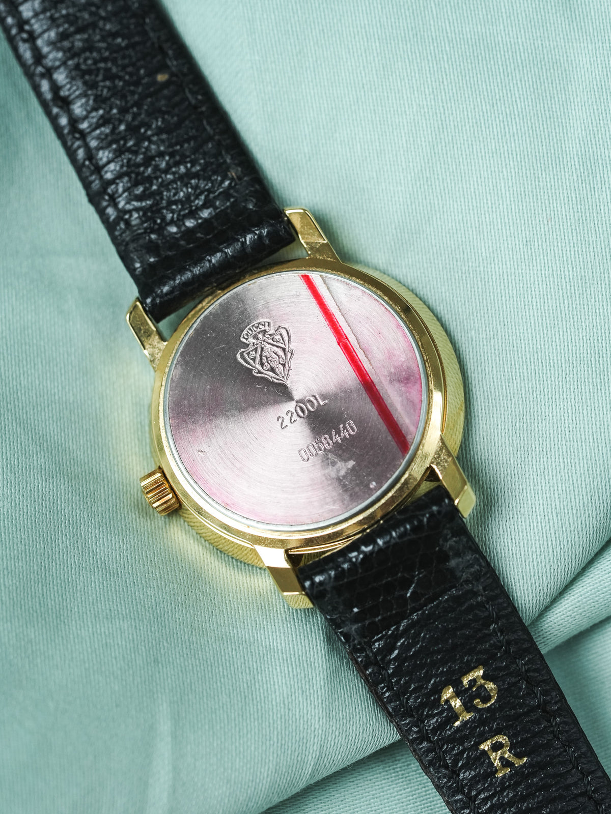 Gucci vintage watch with gold case, black leather strap, and engraved back