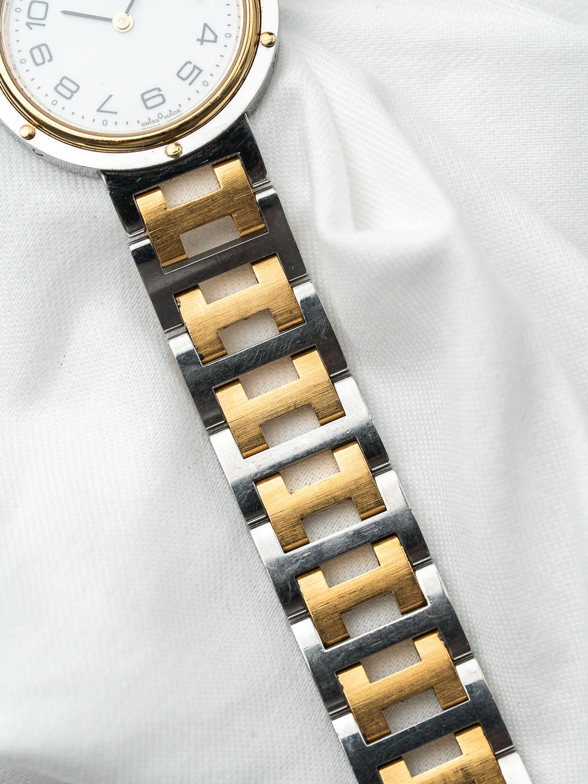 Montre Hermès vintage avec bracelet en acier et plaqué or sur fond blanc