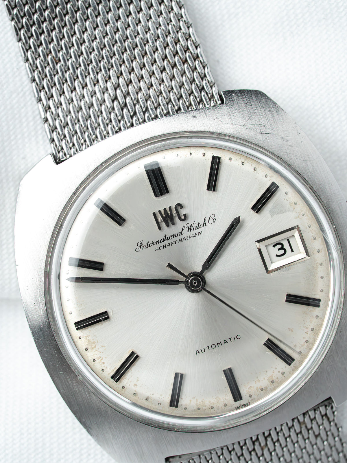 IWC vintage automatic watch with silver dial, black markers, and mesh bracelet