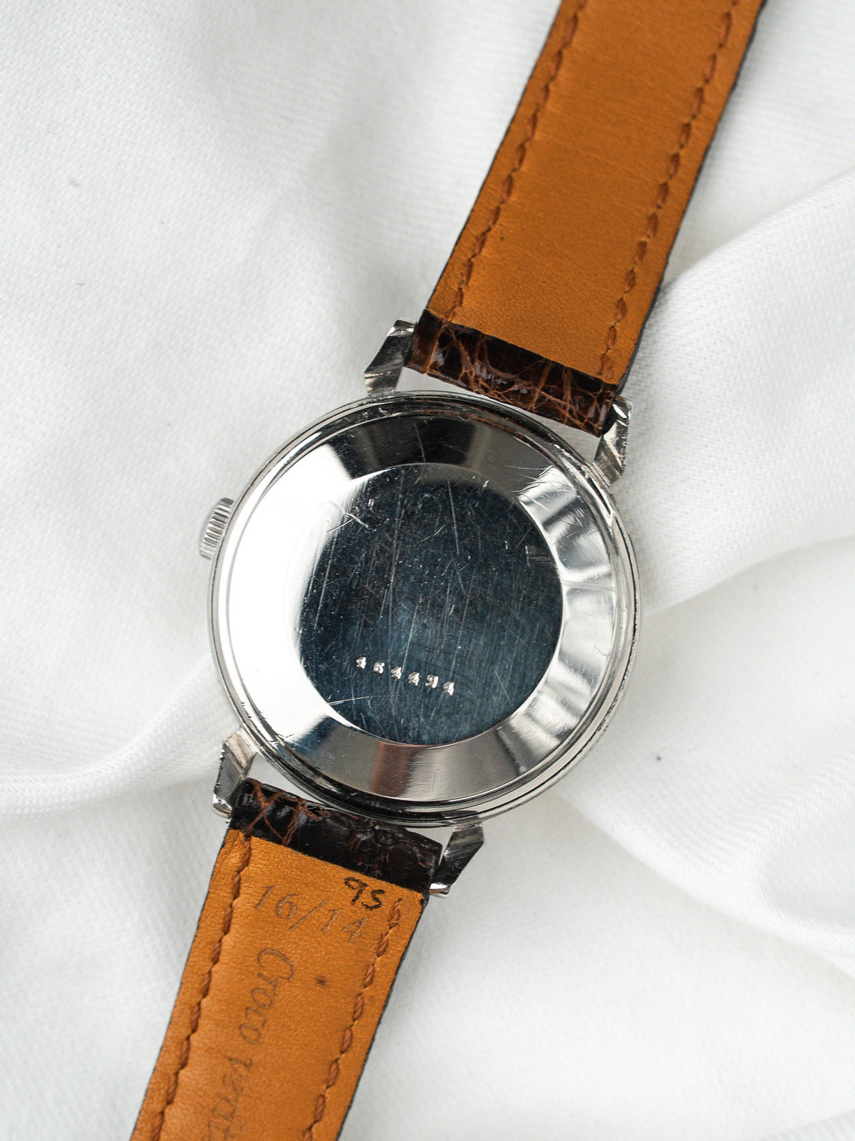 Dos d'une montre vintage en acier avec bracelet en cuir marron sur fond blanc