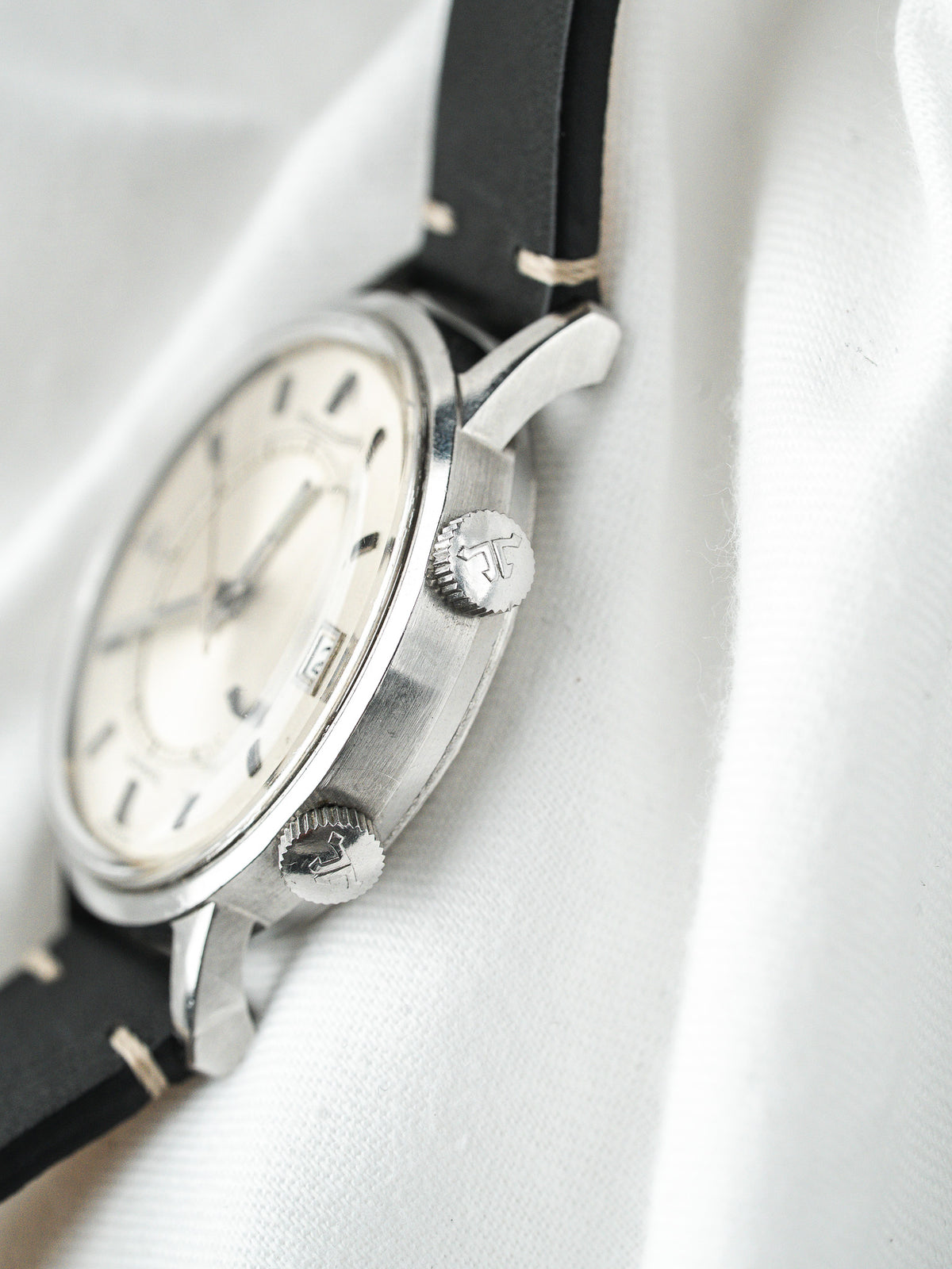 Vintage Watch aus Stahl mit weißem Zifferblatt und schwarzem Lederarmband auf Stoff