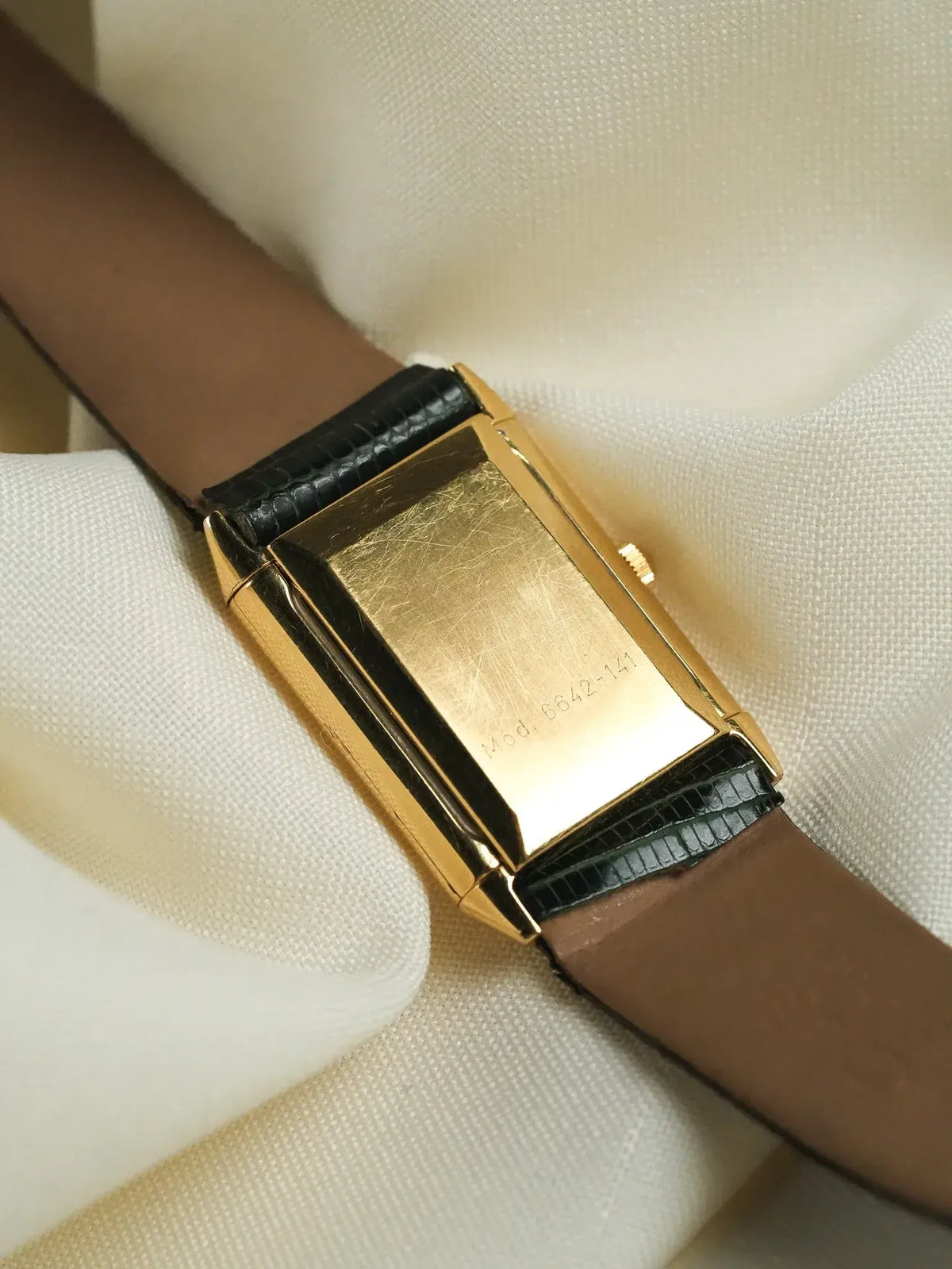 Vintage Universal Genève rectangular gold watch with black leather strap on wrist
