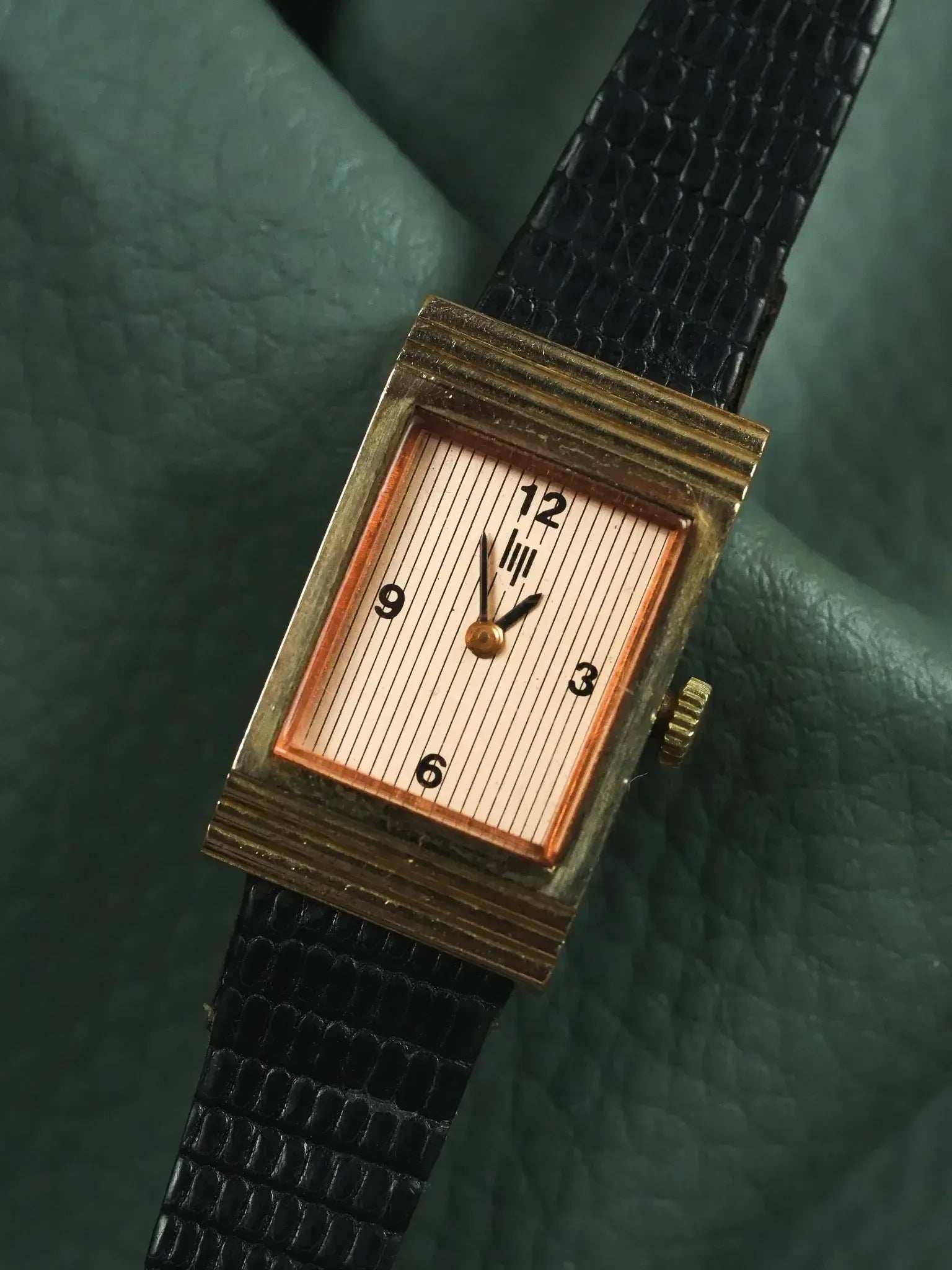Vintage rectangular watch with gold case, striped dial, black leather strap on green leather