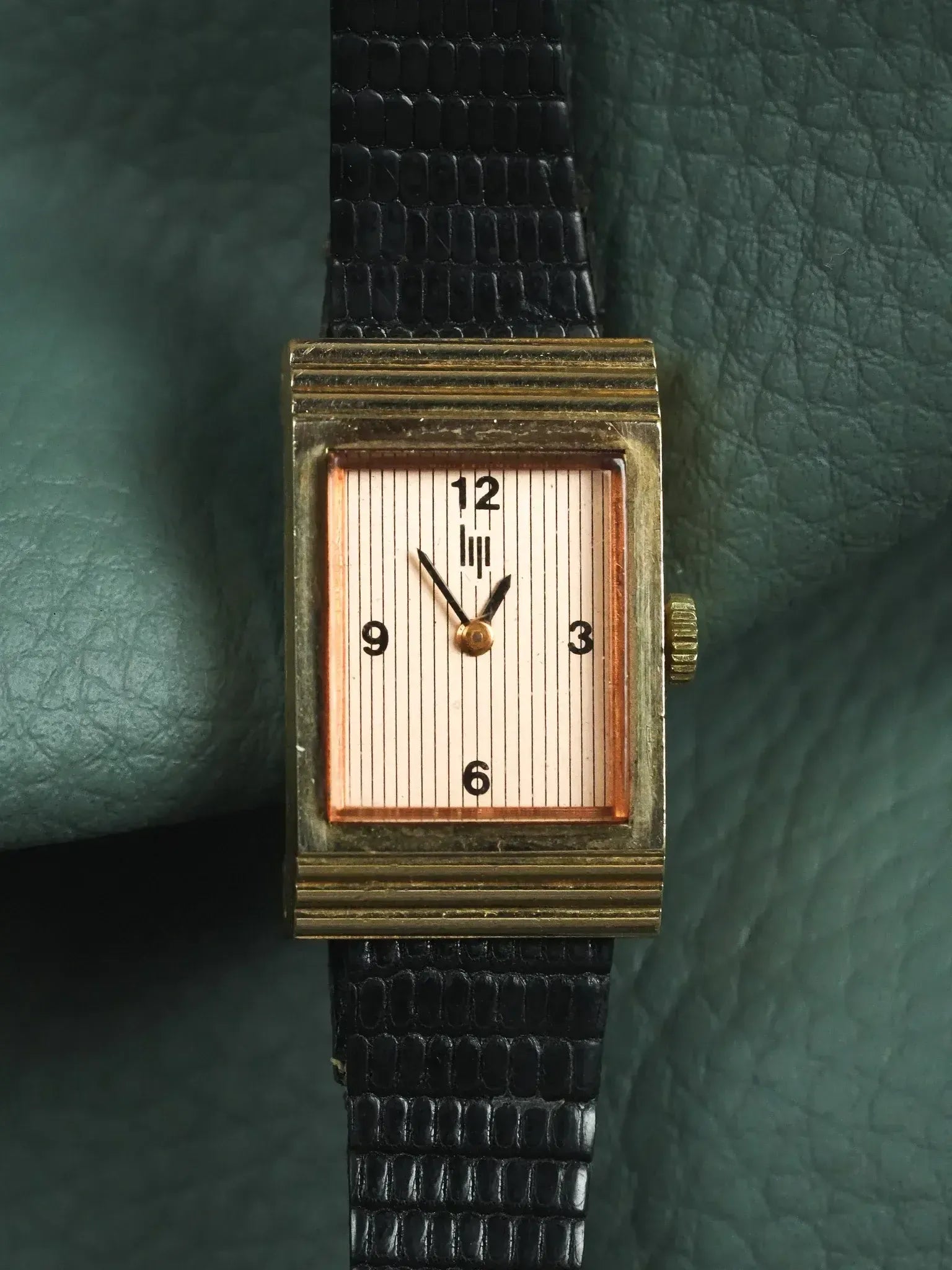 Vintage rectangular watch with gold case, striped dial, black alligator strap on green leather