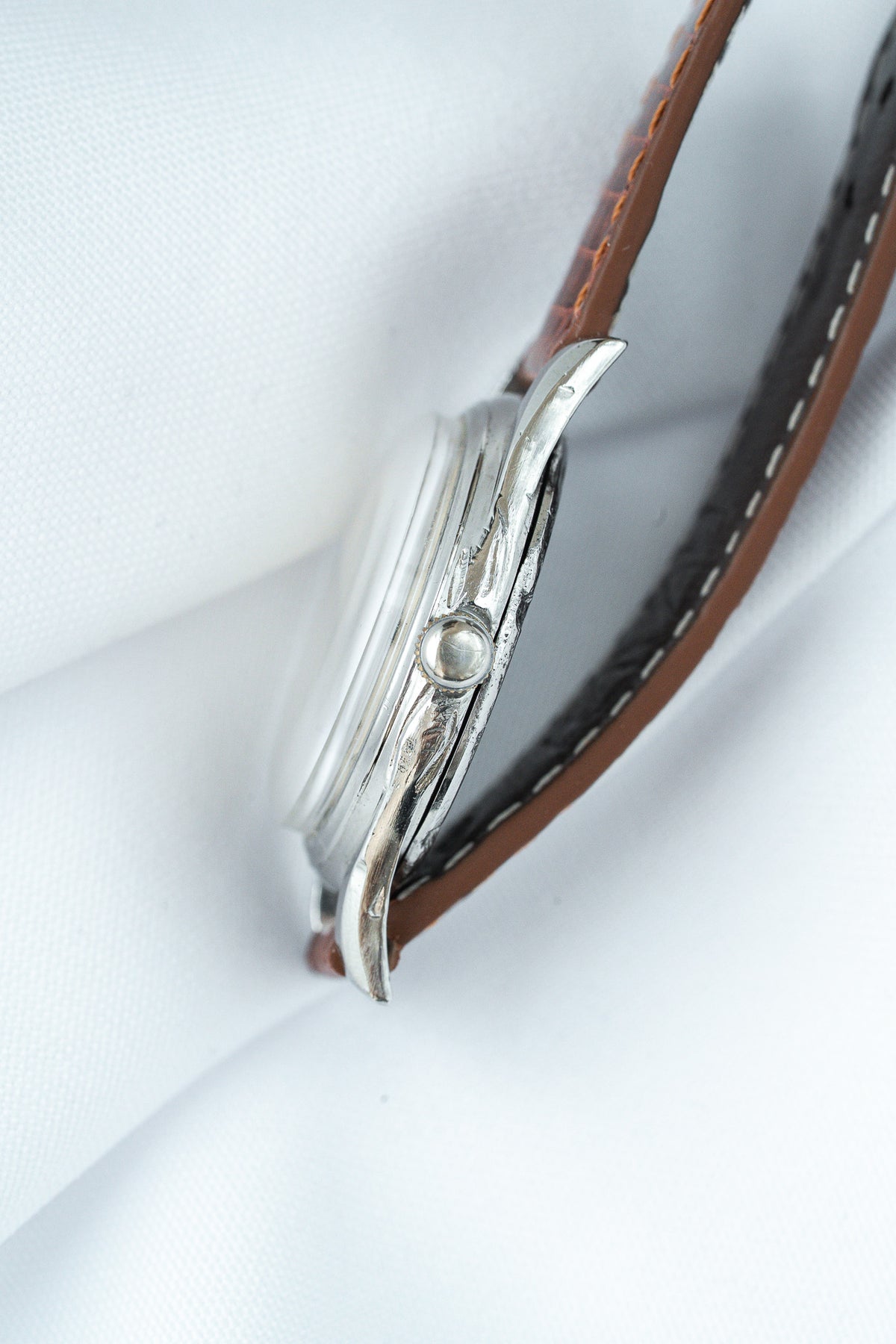 Vintage Cartier watch with silver case, brown leather strap, side profile on white
