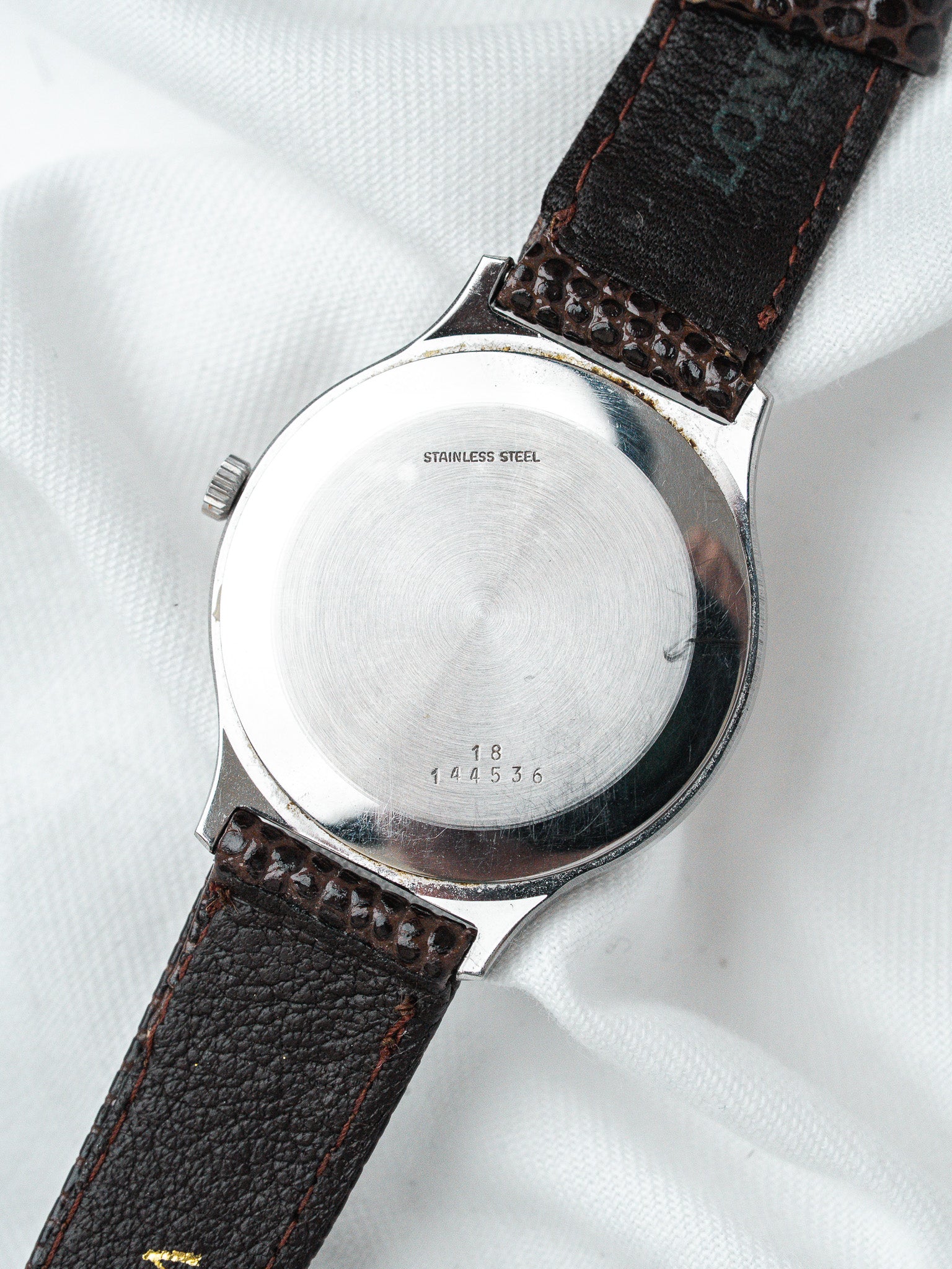 Stainless steel watch back with engraved serial number, brown leather strap