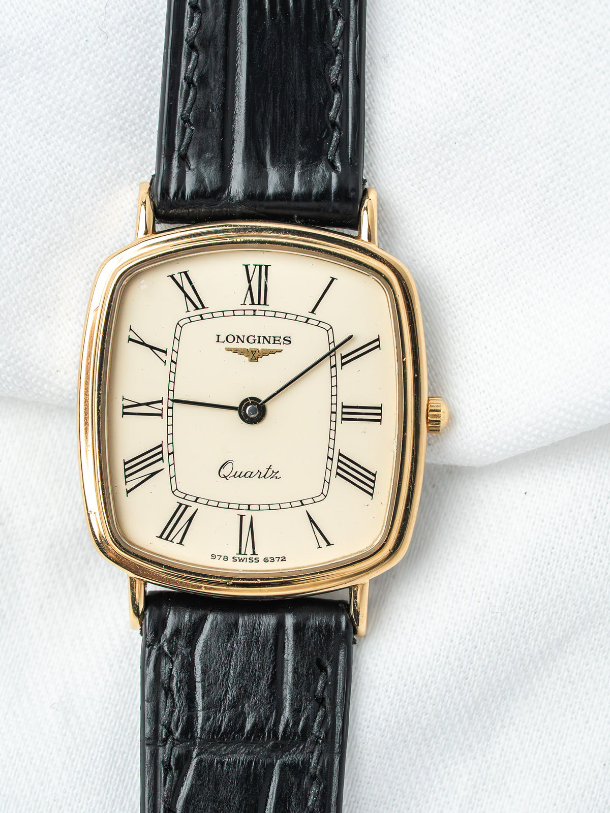 Longines vintage quartz watch with gold case, cream dial, Roman numerals, black leather strap