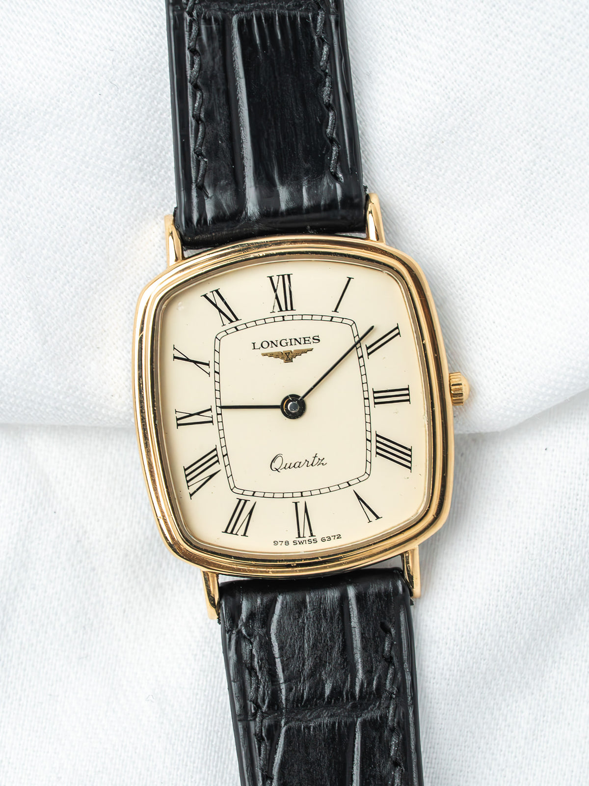 Longines vintage quartz watch with gold case, cream dial, Roman numerals, black leather strap