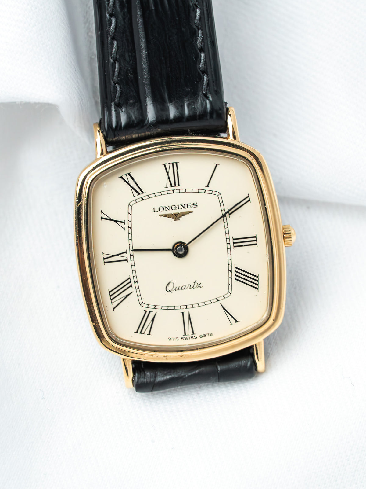 Longines vintage quartz watch with gold case, cream dial, Roman numerals, black leather strap
