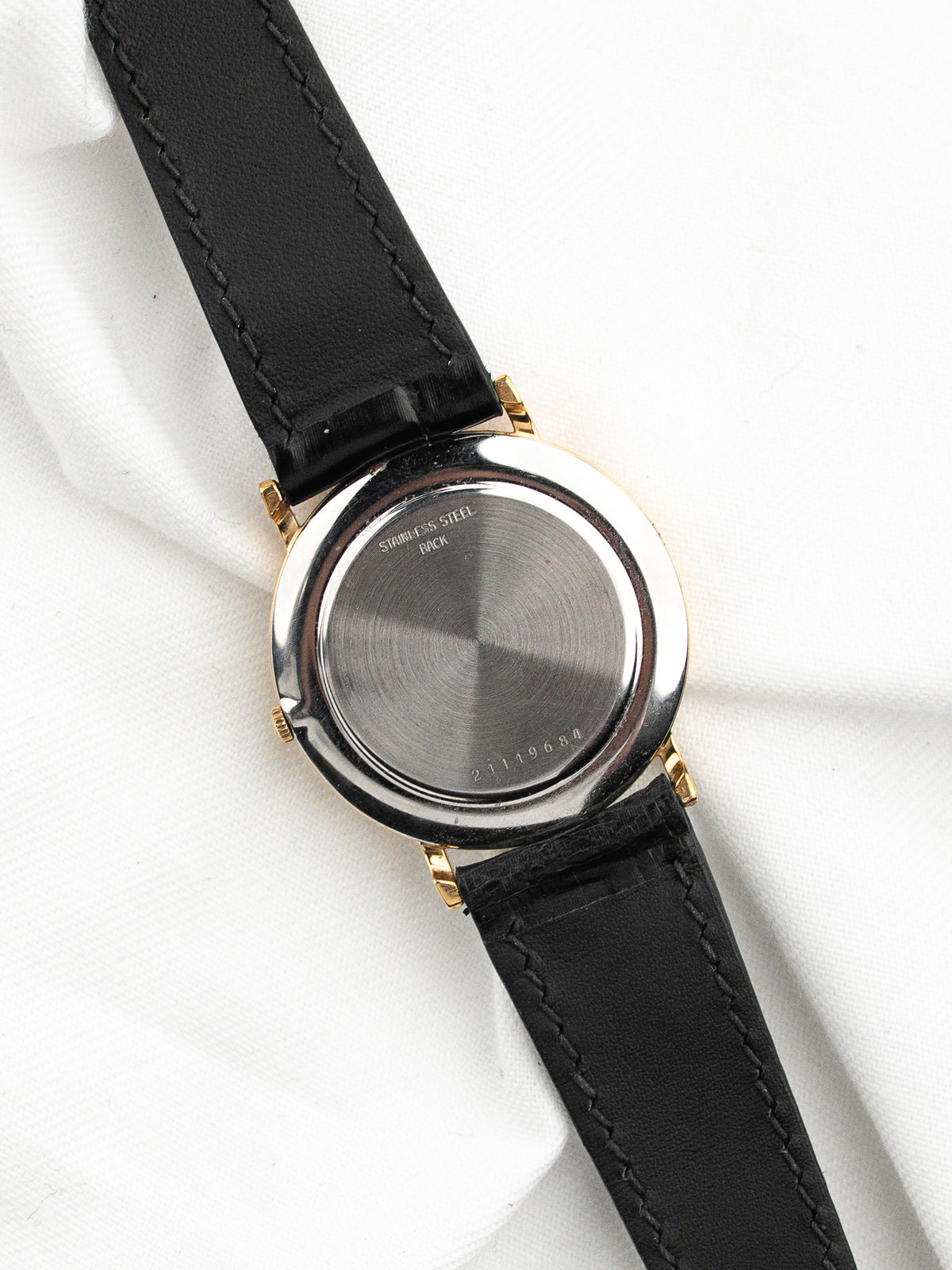 Dos d'une montre vintage avec boîtier doré et bracelet en cuir noir.