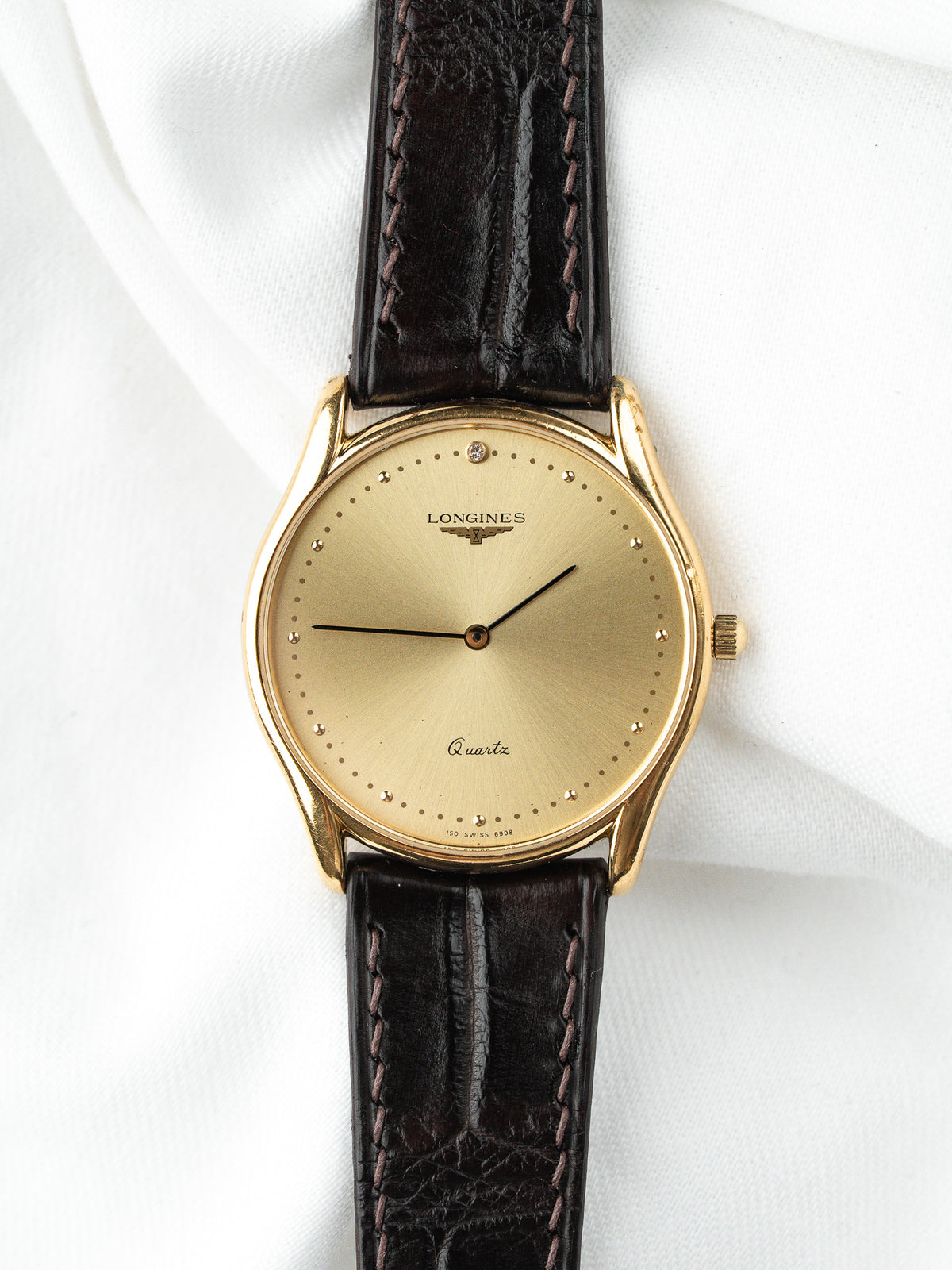 Montre Longines vintage en or, cadran champagne et bracelet en cuir noir