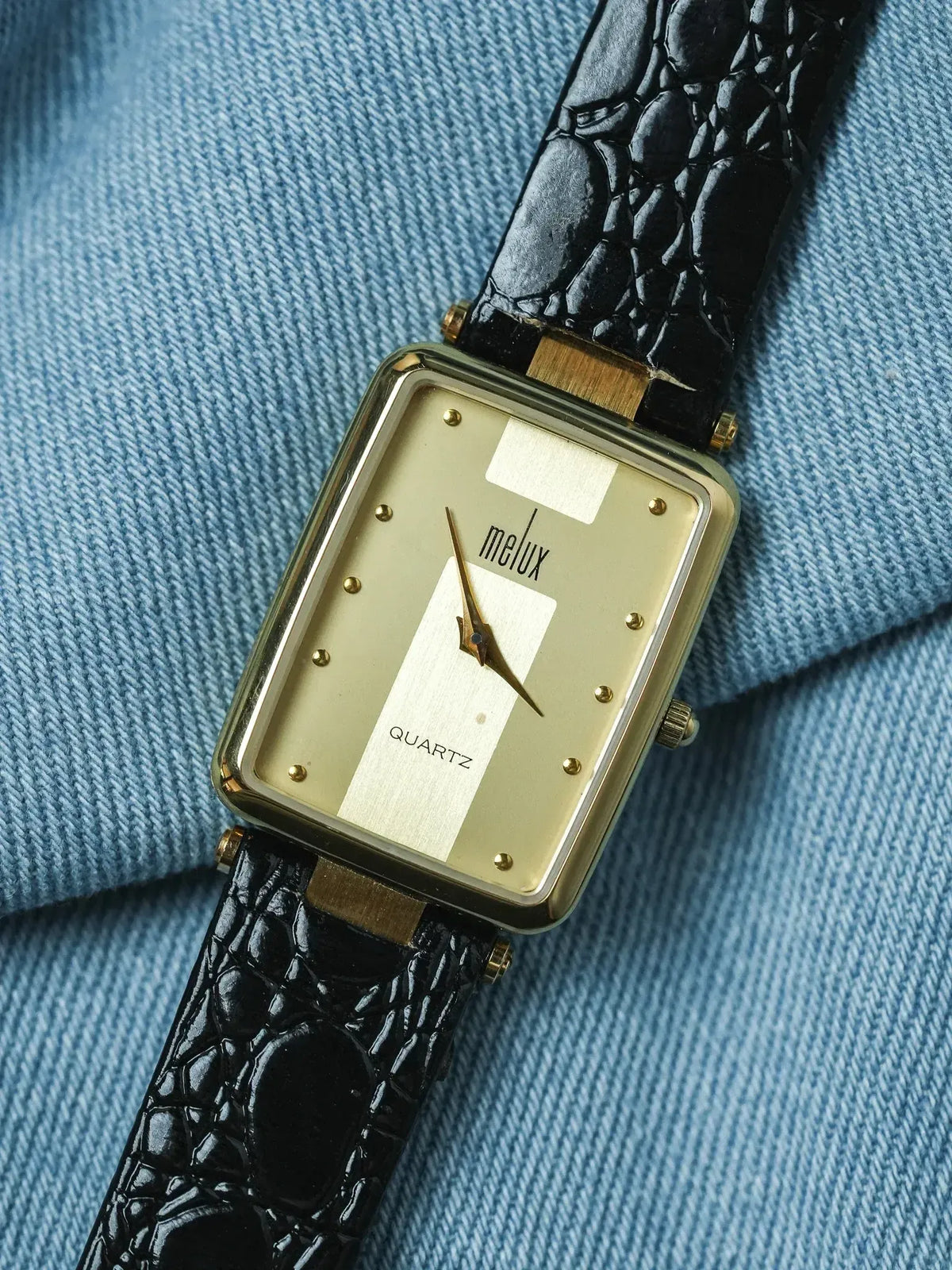 Melux vintage quartz watch with gold case, cream dial, black croco strap on denim