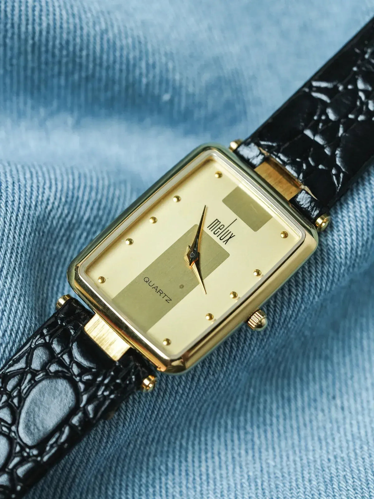 Melux vintage quartz watch with gold case, cream dial, black croco strap on denim