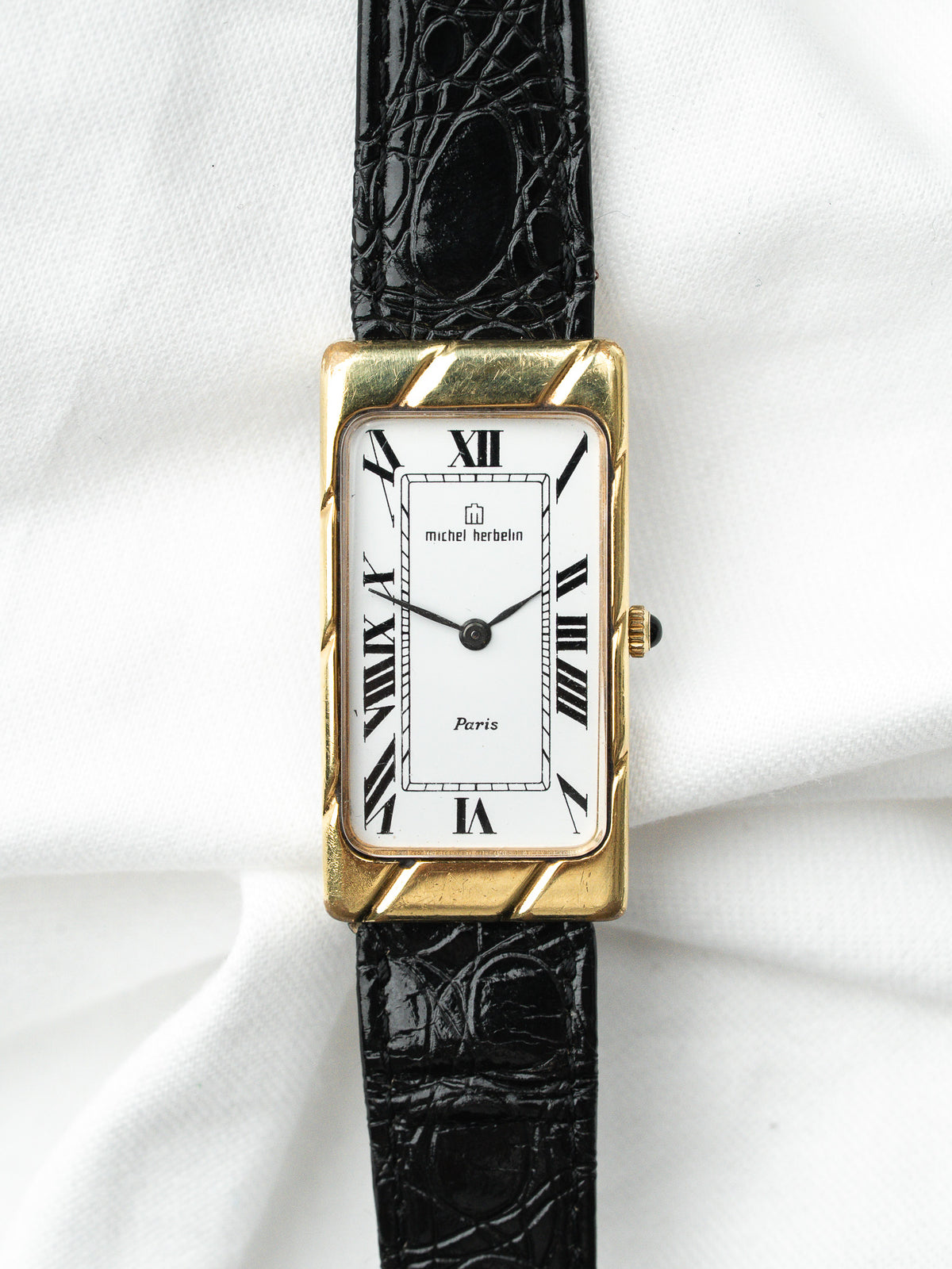 Montre Michel Herbelin vintage, boîtier rectangulaire doré, cadran blanc et bracelet cuir noir