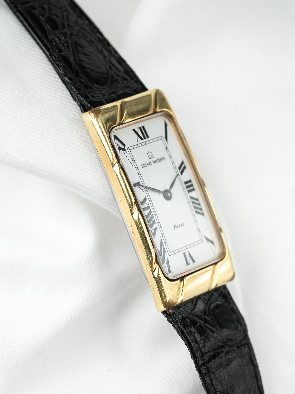 Montre Michel Herbelin vintage, boîtier rectangulaire doré, cadran blanc et bracelet cuir noir